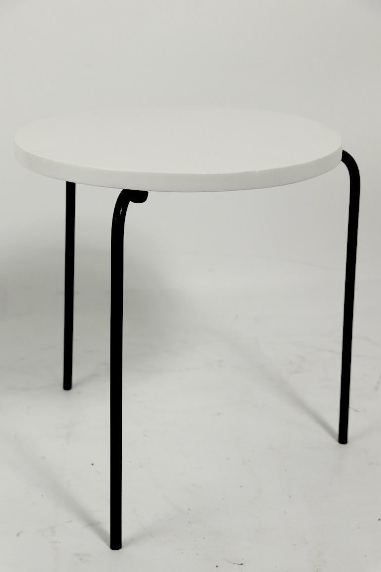 Nice diminutive Mid Century  table having a circular wood top, on wrought iron legs. The top is newly repainted to semi gloss white, the legs to semi gloss black, creating a striking graphic contrast. Measures: Top 14.75 diameter x .75 inch thick.