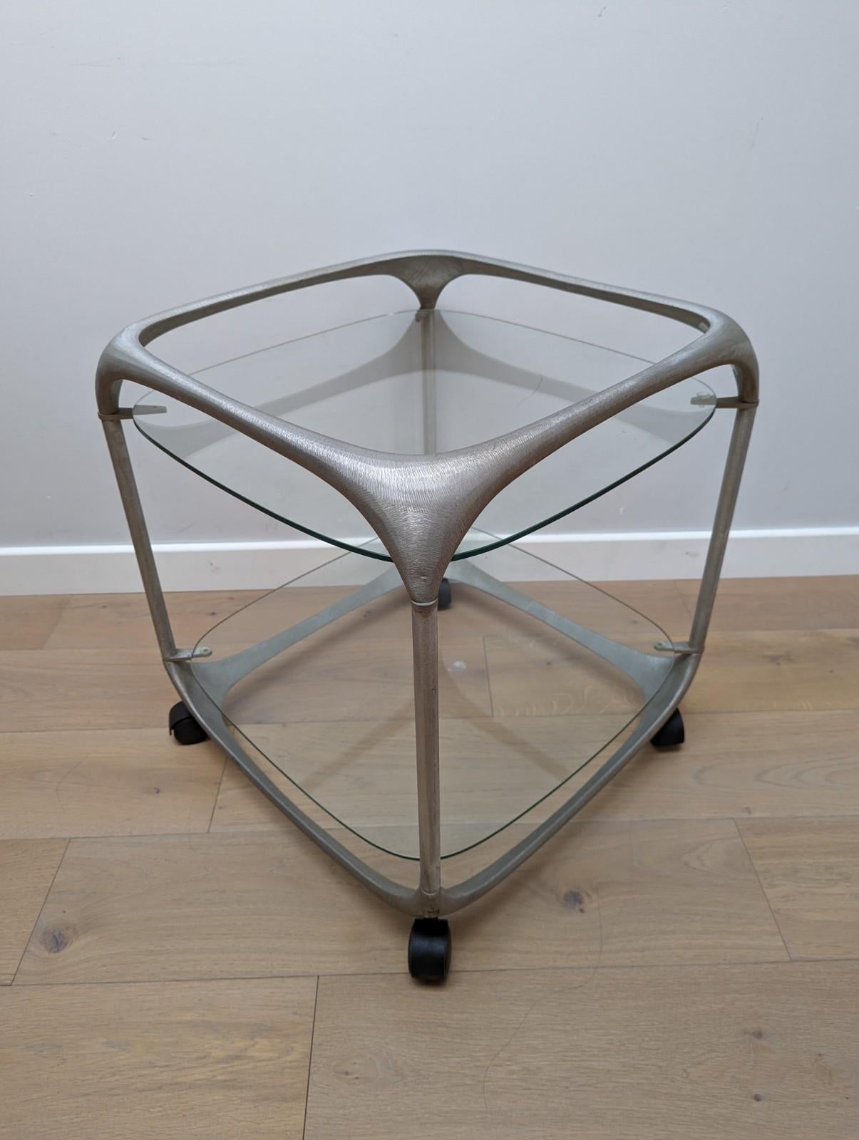 A rare mid-century cube form textured aluminium bar trolley, designed by Lorenzo Burchiellaro. 

Cast Aluminium, with a brushed texture adding depth and interest to the item, with two glass shelves with curved edges which sit on 4 aluminium