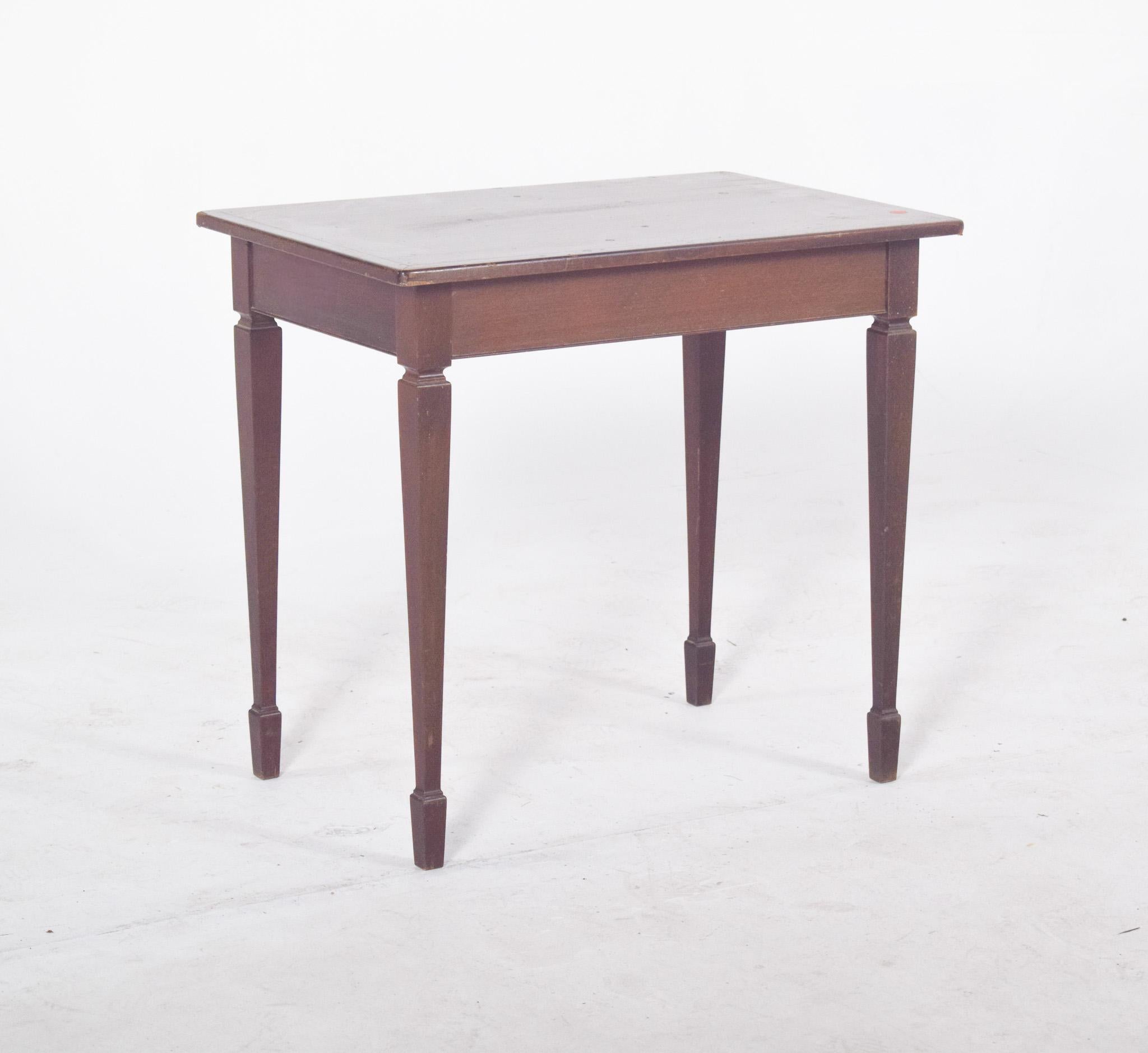 Side table in mahogany. Rectangular, it has straight edges and a flat surface, slightly marked by signs of use such as small stains and scratches. The structure is made up of four slender, elegantly tapered legs with square ends, which give the