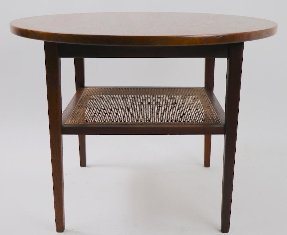 Nice round end, or side, table with circular wood top and cane lower shelf. The top surface is 20 inch H the lower shelf surface is 11 inch high, it is in excellent, original condition, design after Risom, unsigned. Classic midcentury Danish modern
