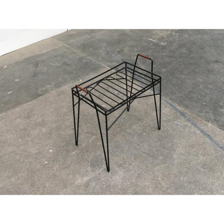 Table plateau ou porte-fleurs en filigrane sur pieds en épingle à cheveux.

La table d'appoint est dotée d'un rebord surélevé et de deux poignées et ressemble davantage à un plateau. L'ensemble de la table est constitué d'une épaisse tige d'acier,