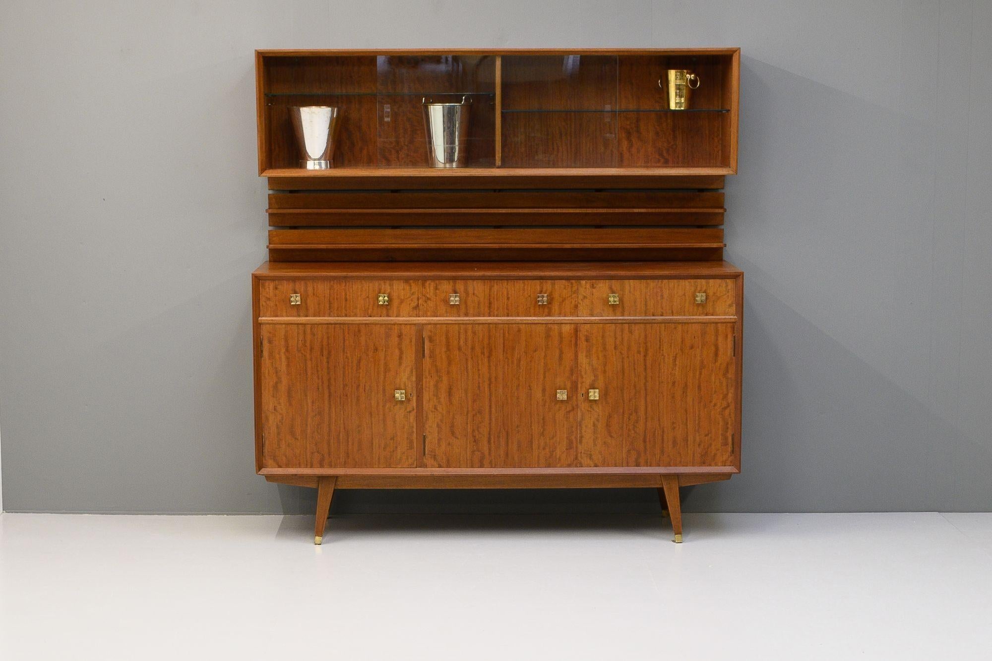 Credenza dal design molto particolare con scaffale e mobile per le bevande. Fantastica qualità, con impiallacciatura in legno di eucalipto. Composto da tre grandi armadi a ripiani e tre cassetti, con un sistema di scaffalature al di sopra con due