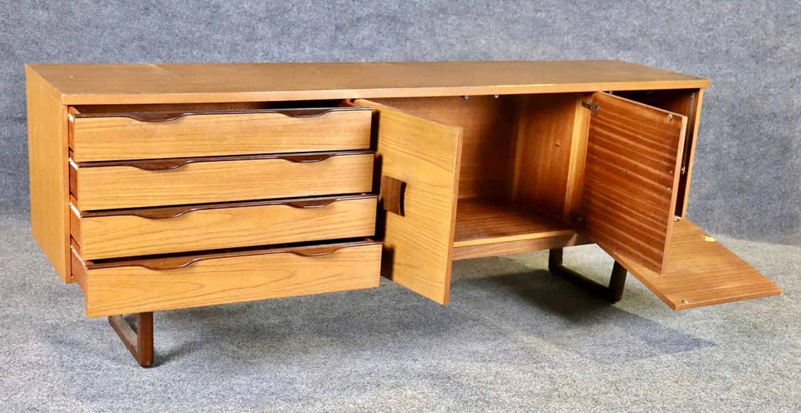Credenza lunga in teak del produttore britannico Europa Furniture. Poggia su una base a cavalletto e presenta quattro cassetti e due armadietti. Le ampie maniglie in palissandro compensano la leggera venatura del teak.
Si prega di confermare la