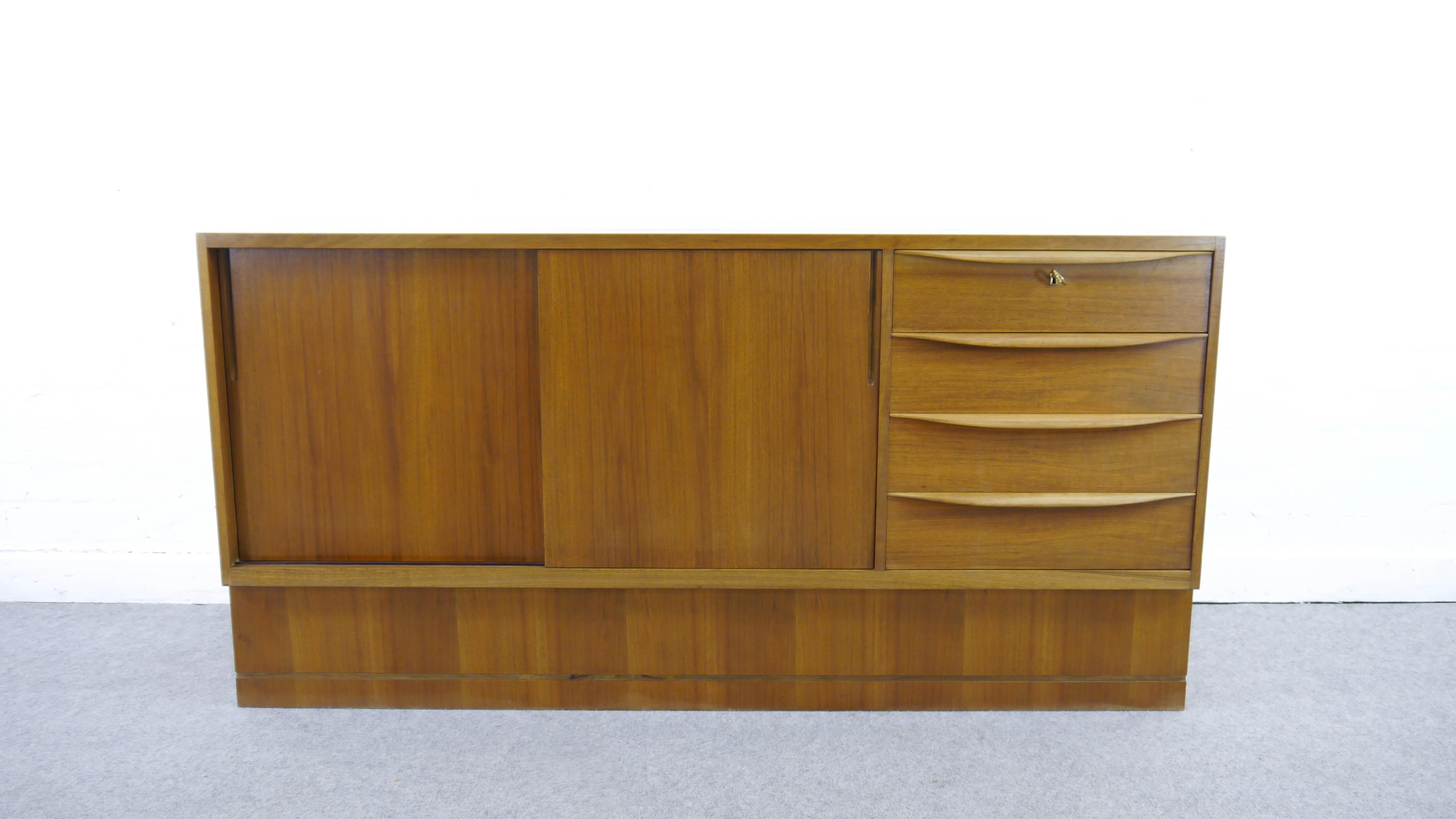 Franz Ehrlich, élève du Bauhaus, a conçu cette série de meubles au début des années 50 pour le VEB Deutsche Werkstätten Hellerau. Buffet du milieu du siècle avec deux portes coulissantes et 4 tiroirs.