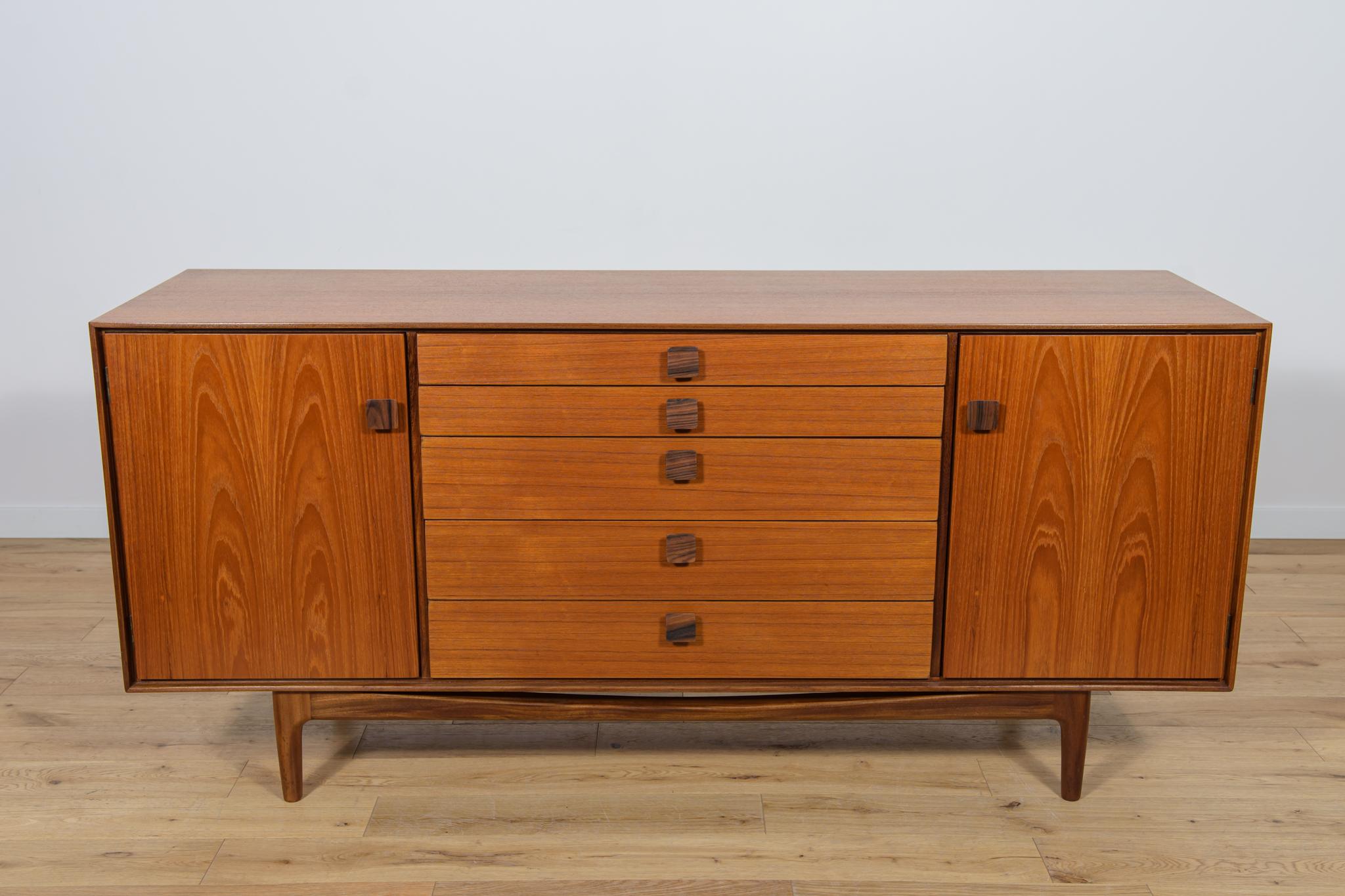 This magnificent mid-century Danish design sideboard credenza was designed by Ib Kofod-Larsen and manufactured by G-Plan circa 1960. It is made of African teak, handles made of rosewood. Features two doors as well as five drawers. Wood elements have