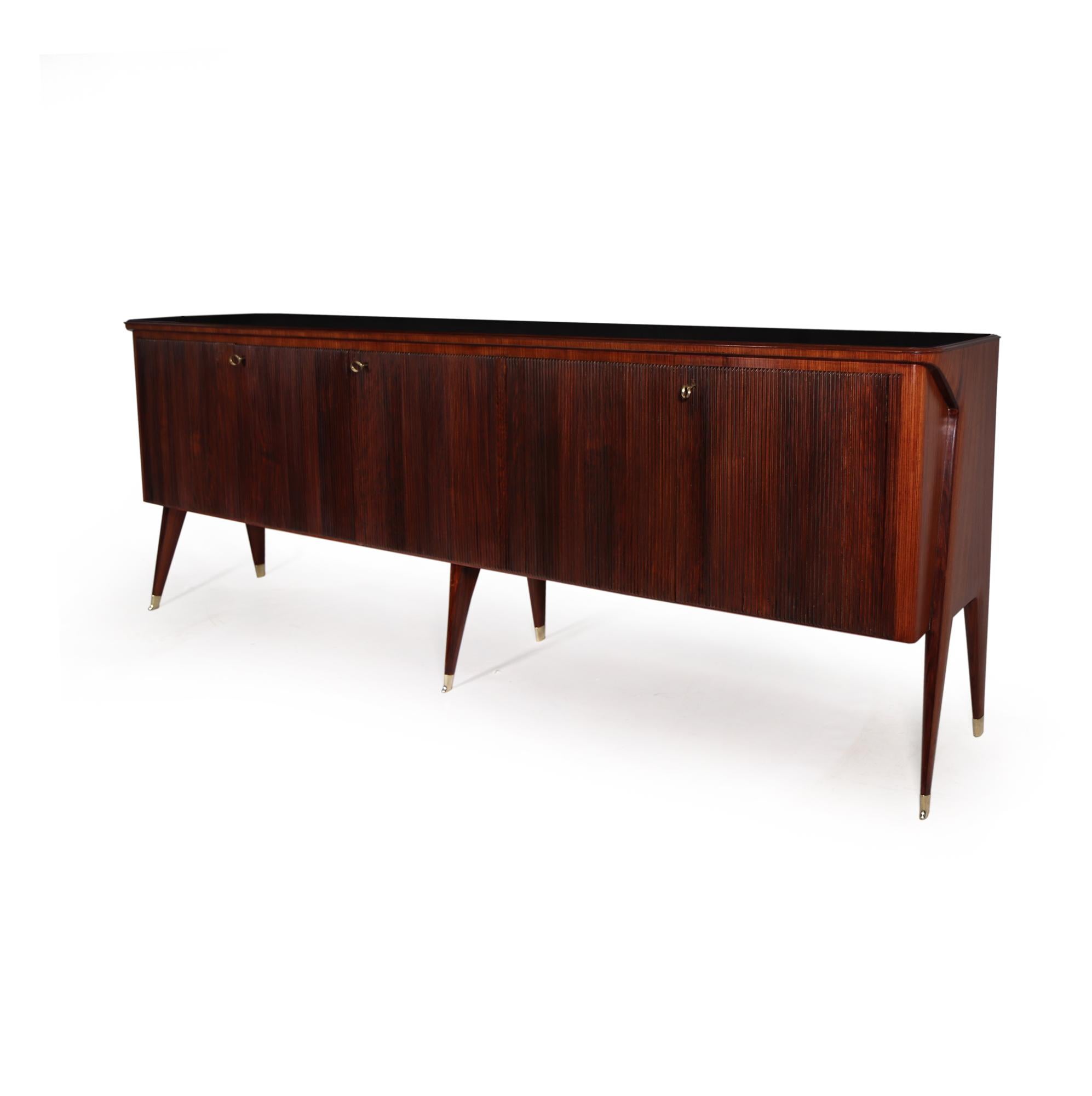 Produced in Italy in the 1950’s with five reeded doors and six legs and having a black glass top and brass sabots this is a large and important sideboard by master craftsman Vittorio Dassi

The sideboard has been fully polished, restored where