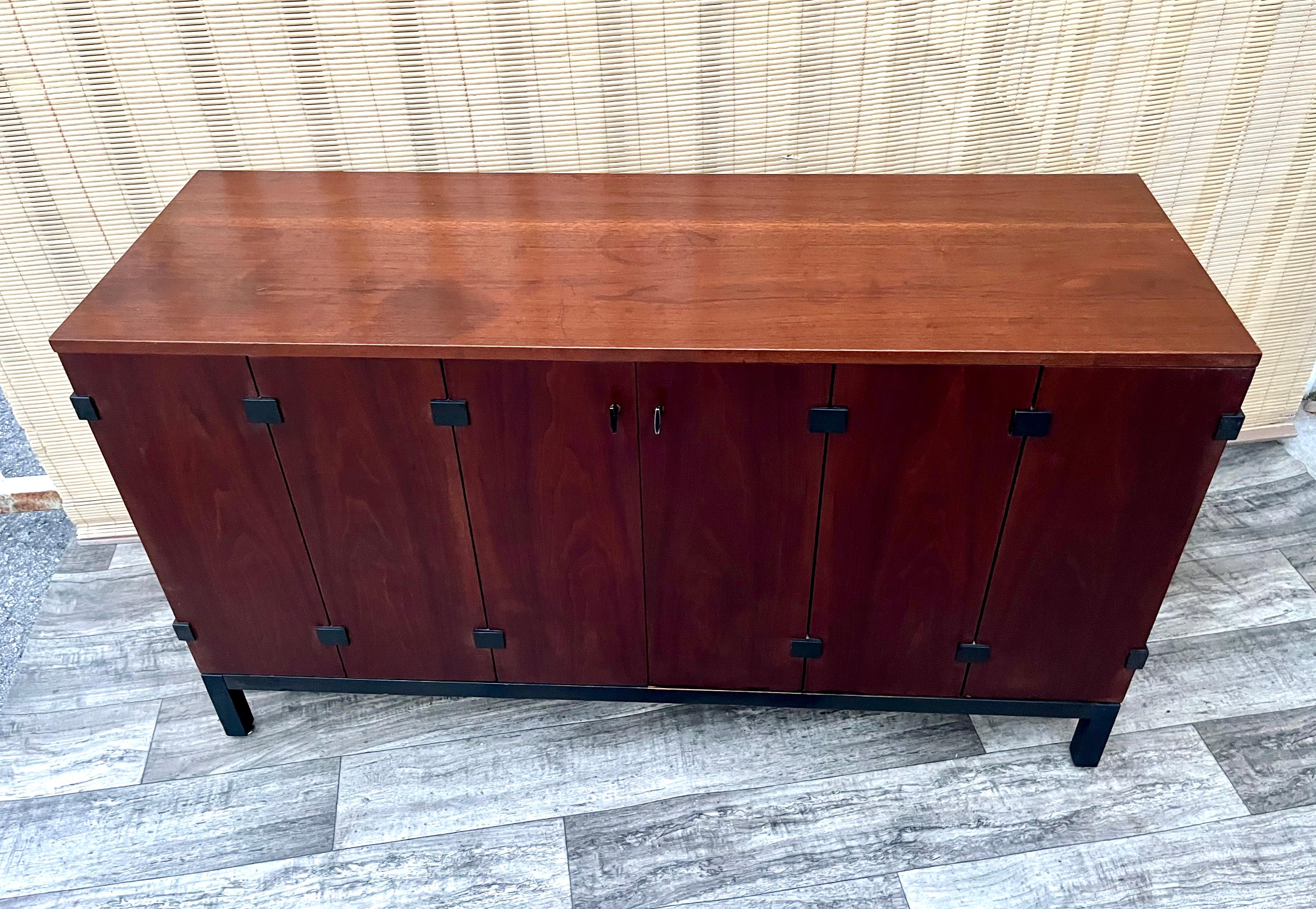 Mid Century Sideboard Credenza by Milo Baughman for Directional. Circa 1960s
Features a sleek Mid Century Modern Design with a beautiful walnut woodgrain, two trifold doors with flat black hardware, two side cabinets with adjustable shelves, and