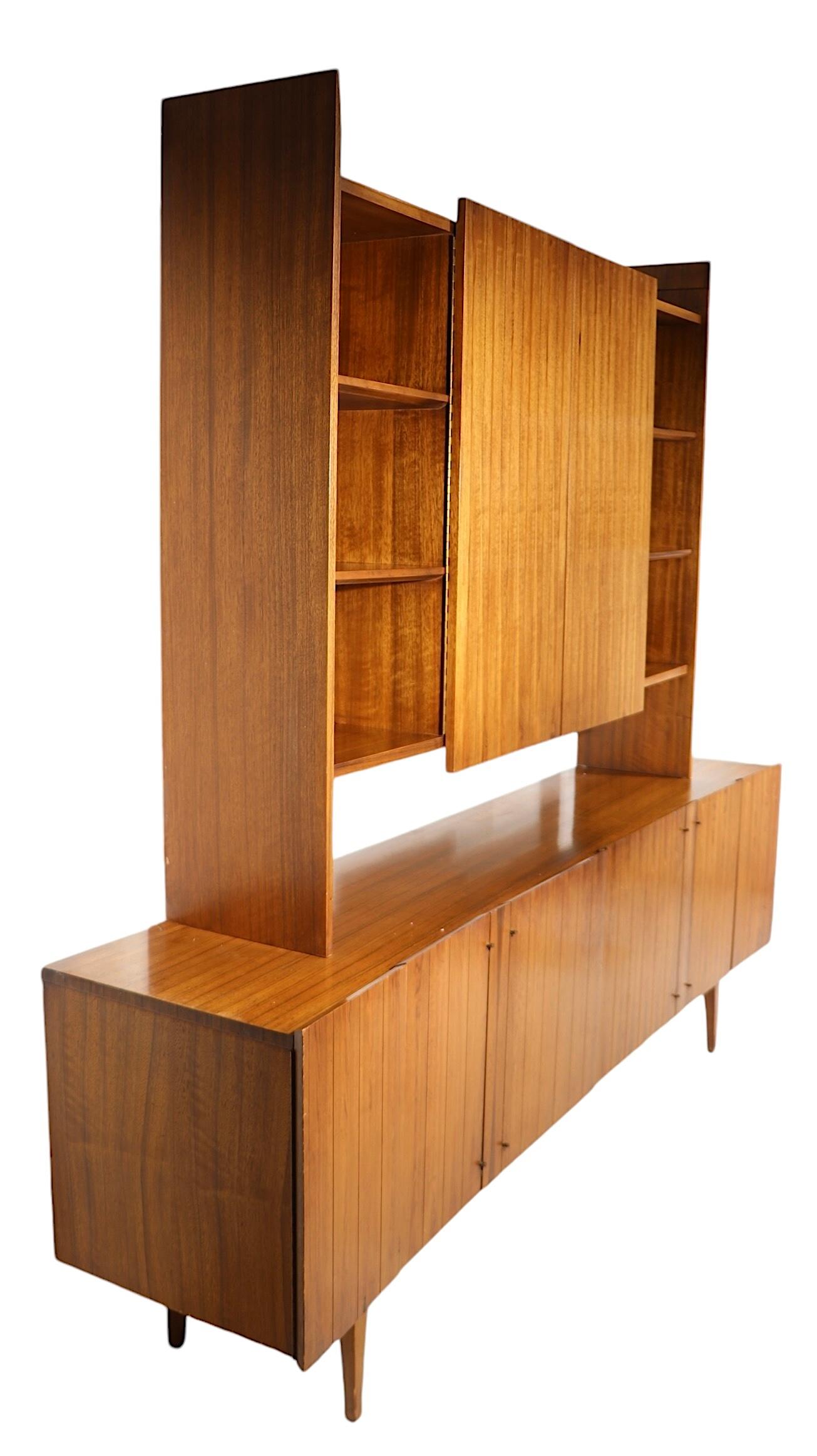Chic, architectural scale sideboard, server, credenza featuring a bottom cabinet with a stylized concave front, which supports a shelf unit with two large swing out doors. The lower section has six doors, which open to reveal three interior storage