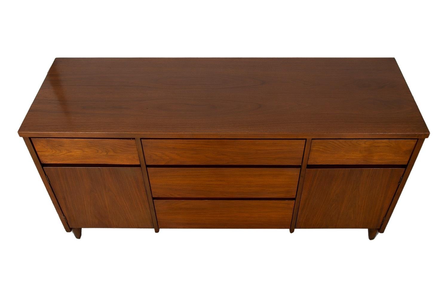 Elegante credenza degli anni '60 di Stanley Furniture. Un profilo minimalista di ispirazione danese moderna, con una costruzione e uno stile eccezionali. Presenta un piano rettangolare con tre cassetti centrali. I cassetti centrali sono affiancati