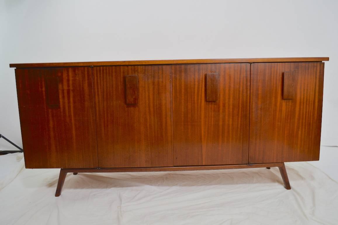 Four-door credenza, opens to reveal shelved storage and interior drawers. This example shows cosmetic wear to the finish, as shown. Design after Kagan, classic 1950s lines, good usable size.