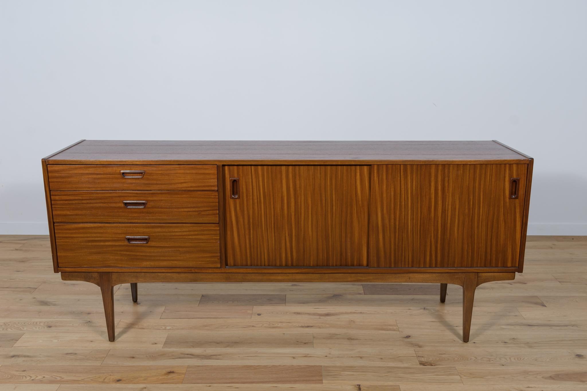 
This vintage sideboard in teak was produced in Great Britain by the manufacturer Nathan in the 1960s. It has two sliding doors and three drawers. The teak elements have been cleaned and painted in an oak mordant and polished with Rustins oil.
