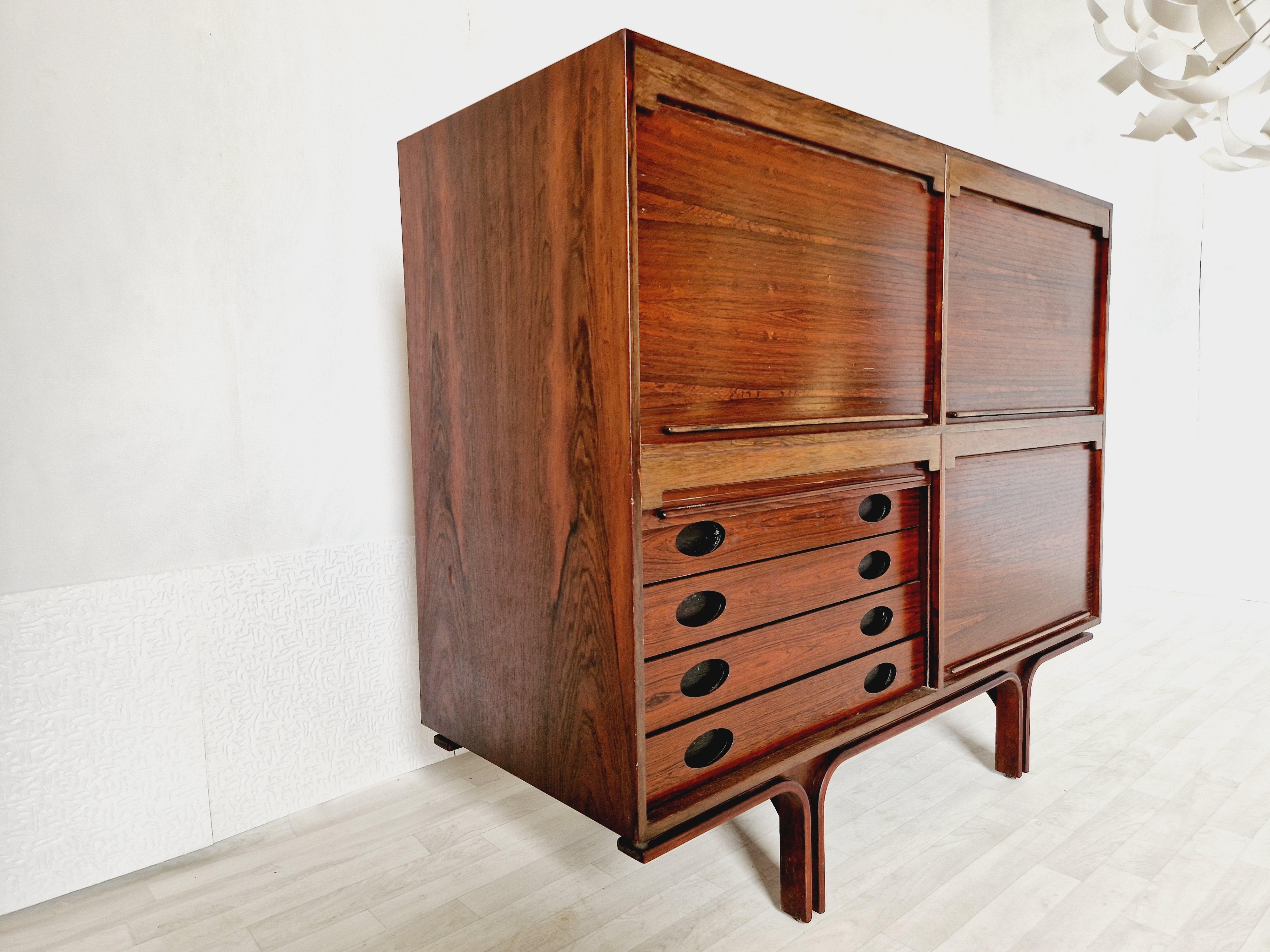 
This stunning vintage sideboard is a true statement piece for any room. It has a beautiful Rosewood finish and smooth features, with cup handles that add a touch of mid-century modern style. There are three compartments with shelves and one with 4