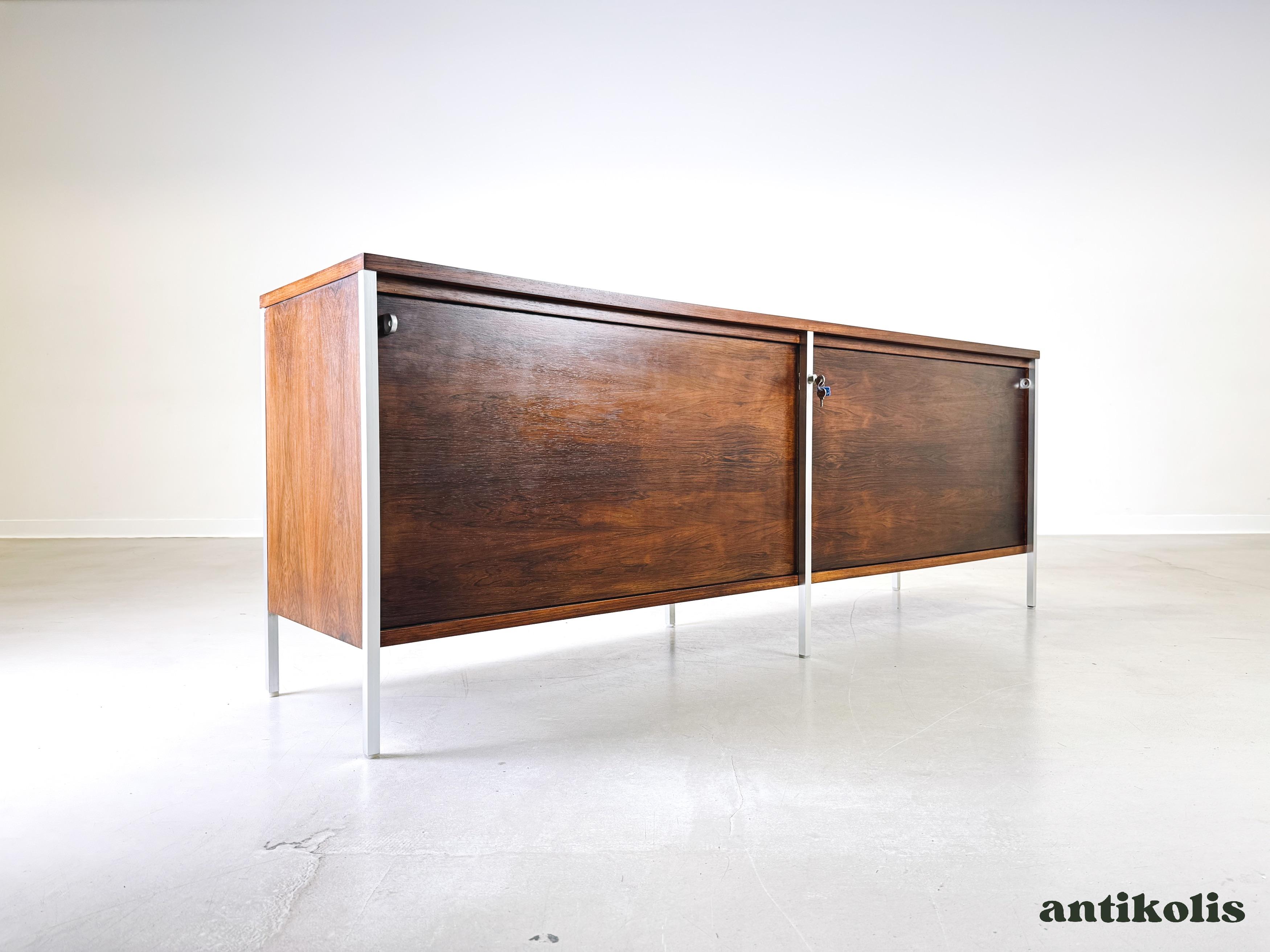 Mettiamo in vendita una bellissima credenza di metà secolo realizzata da Herber Hirch per Holzäpfel KG. Questo modello estremamente raro è realizzato in palissandro di alta qualità e gambe in acciaio cromato. Il design puristico e senza tempo e i