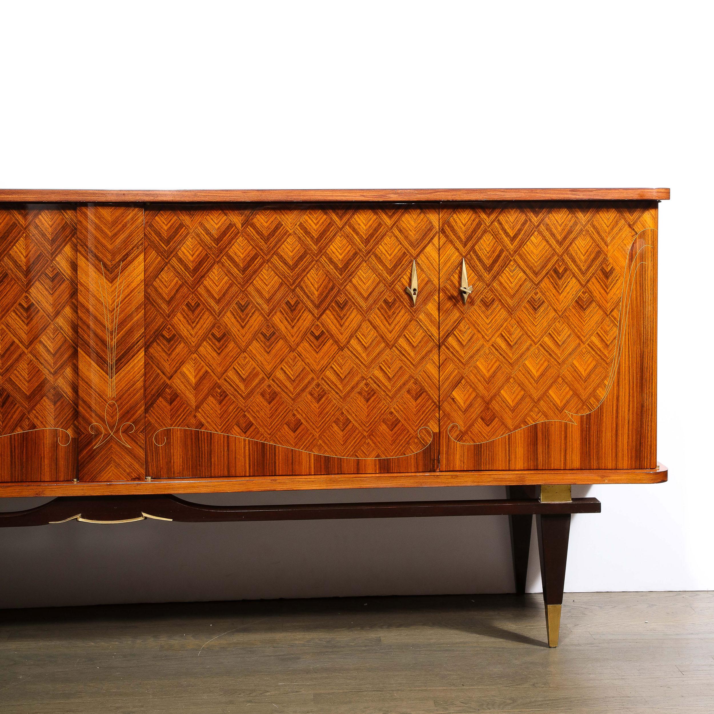 This stunning and dramatic Mid-Century Modern sideboard was realized in France circa 1950. It features four volumetric tapered rectangular legs sittings on robust brass sabots of the same form that connect to a floating sculptural apron- all in