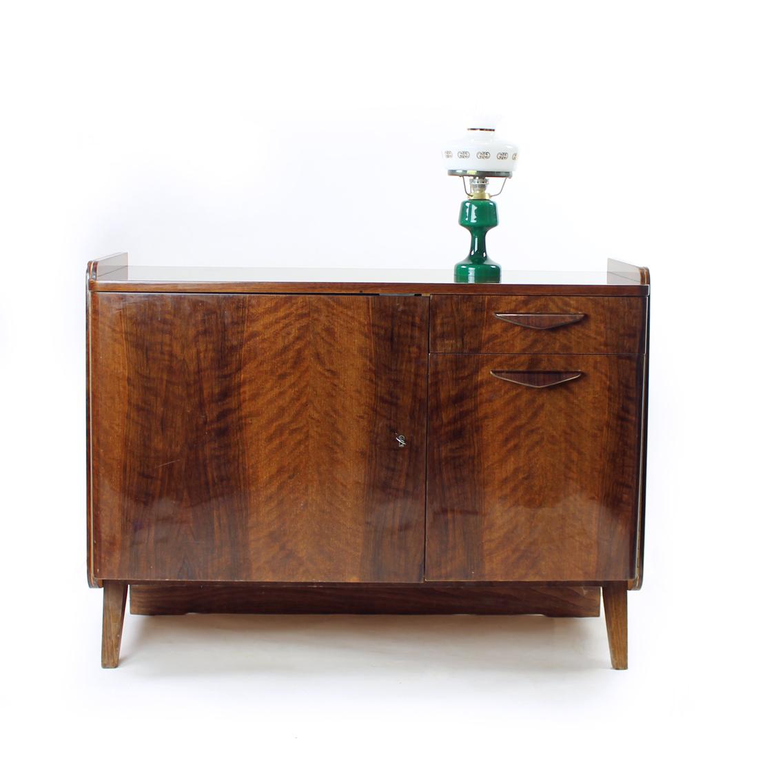 Beautiful midcentury sideboard in a dark walnut wood veneer. Produced by Tatra company in Czechoslovakia. Original label still partially attached on the back with the year of the production visible. The sideboard stands as a solid and beautiful