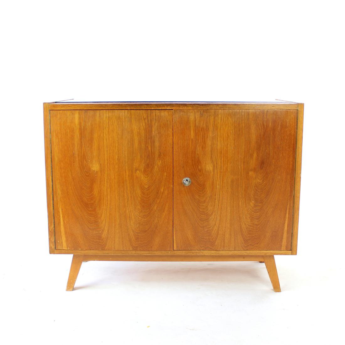 Mid-century sideboard in elegant finish. Produced in Czechoslovakia in 1960s, the sideboard is made of oak wood construction with beautiful veneer. The sideboard has two doors working on piano hindges. The lock is original and works without a