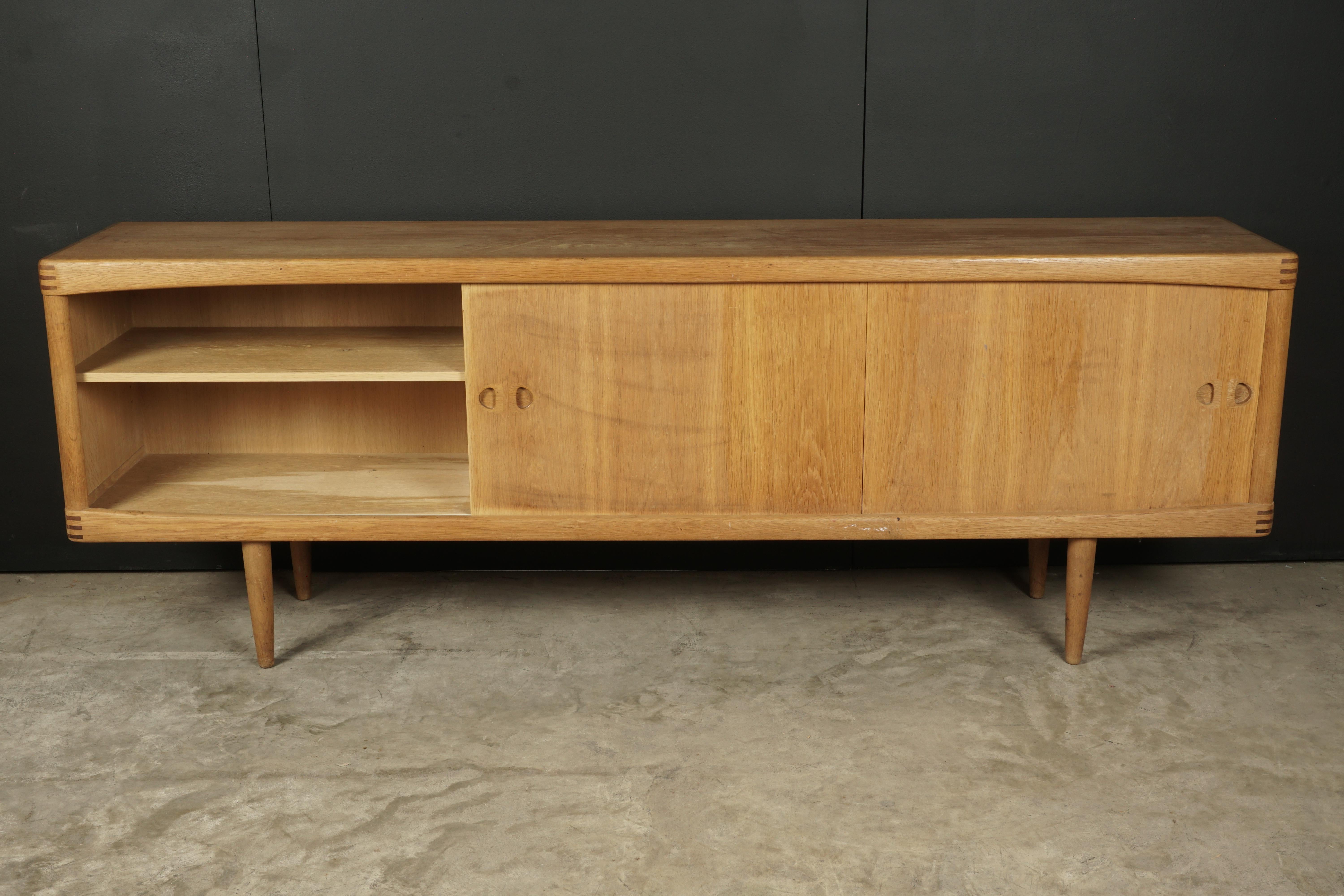 Midcentury sideboard in oak, designed By H. W. Klein, Denmark, 1960s. Solid oak construction with four drawers and two sliding doors. Produced by Bramin Møbler.