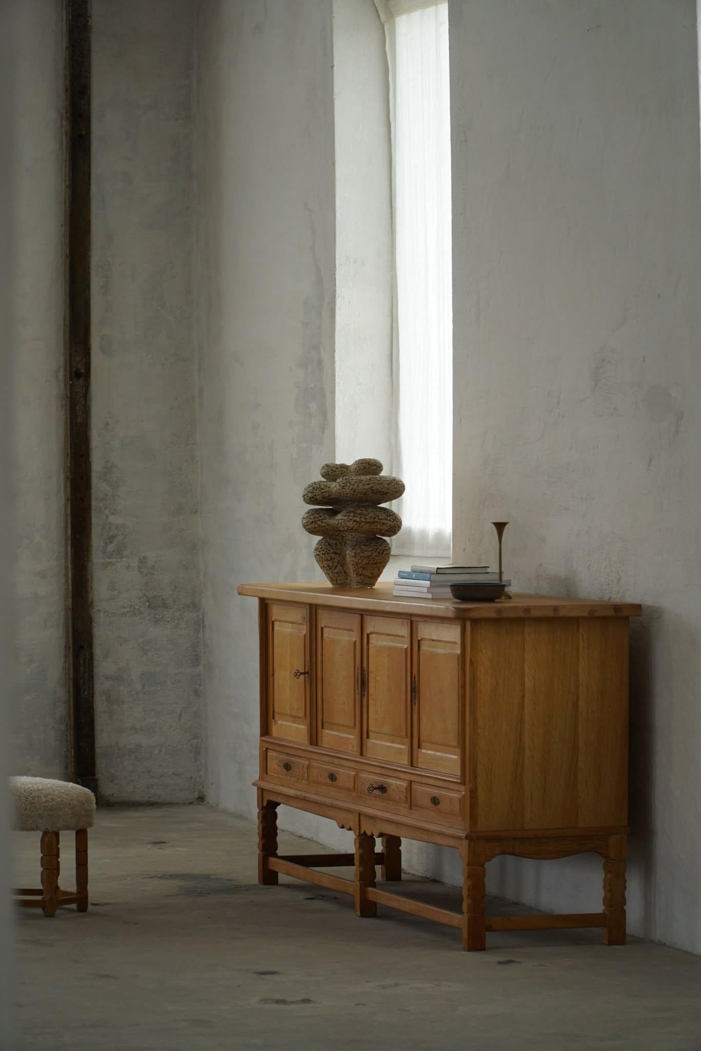 A large rectangular classic sideboard / cabinet in oak with plenty of storage and a refined carved front design. Made by a Danish cabinetmaker in the 1960s. 
This piece is in a good vintage condition with a few marks on the top surface.

This