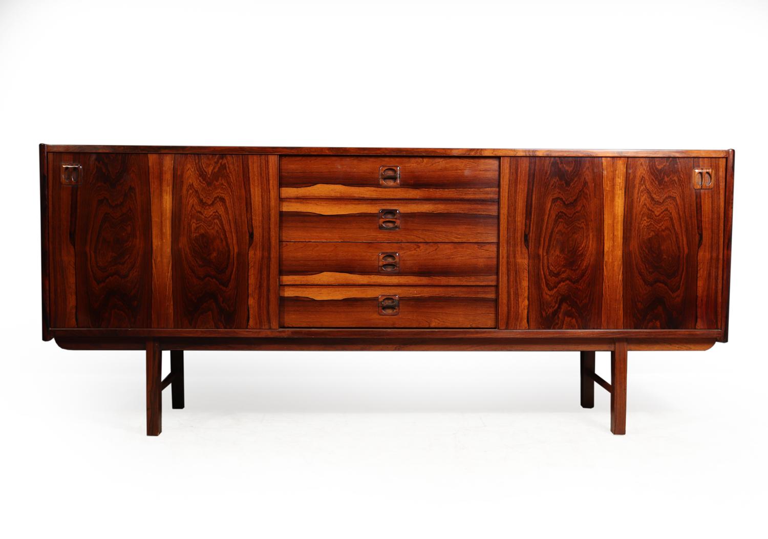 Midcentury sideboard in rosewood Denmark circa 1960
Original, midcentury, Danish, rosewood sideboard, from the 1960s with sculpted rosewood handles. Sideboard comprises of four central drawers and two sliding doors either end. All of the drawers