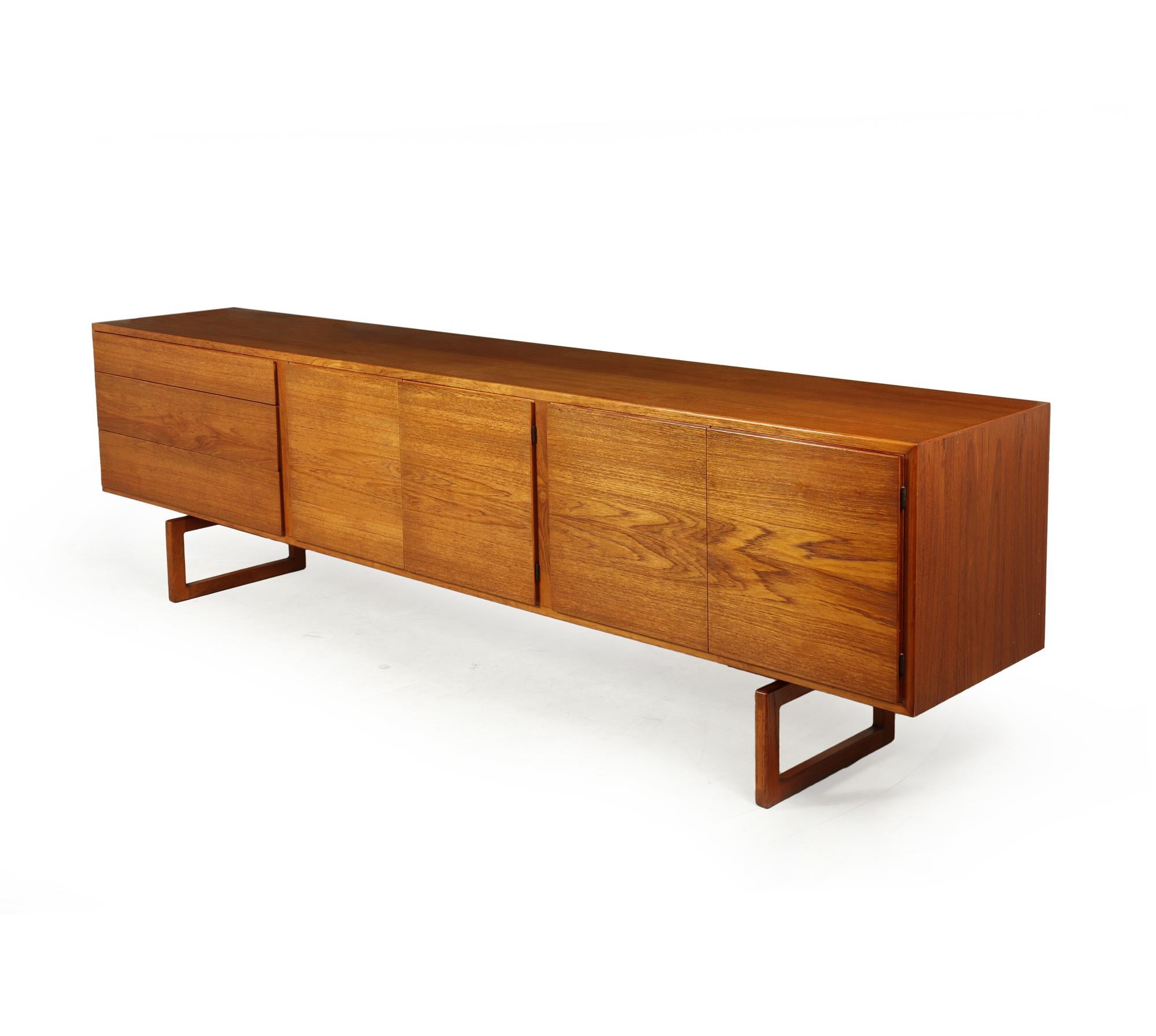 This sideboard was designed by Arne Hovman Olsen and prouced by Mogens Kold in the mid 1960’s in Denmark, the sidebord has four doors with adjustable shelves behind, to the left are three graduating drawers all these have finger grip edging making