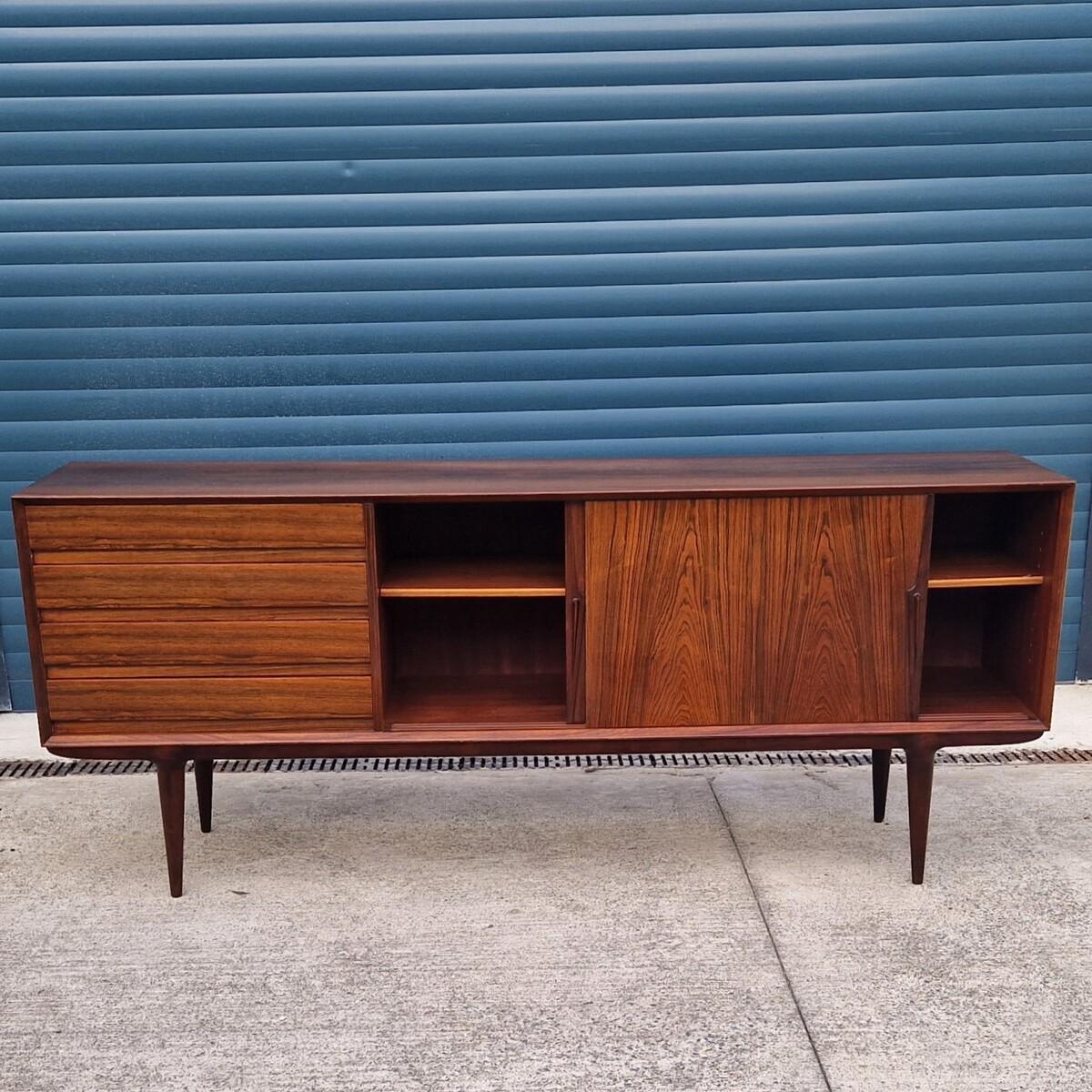 Mid-Century Sideborad of a rare elegance, model 18, designed in 1958 for Omann Jun. This sculptural model lays on tapered copass-shaped footing. It is comprised of four drawers on the left side and two sliding doors revealing a storage room. That