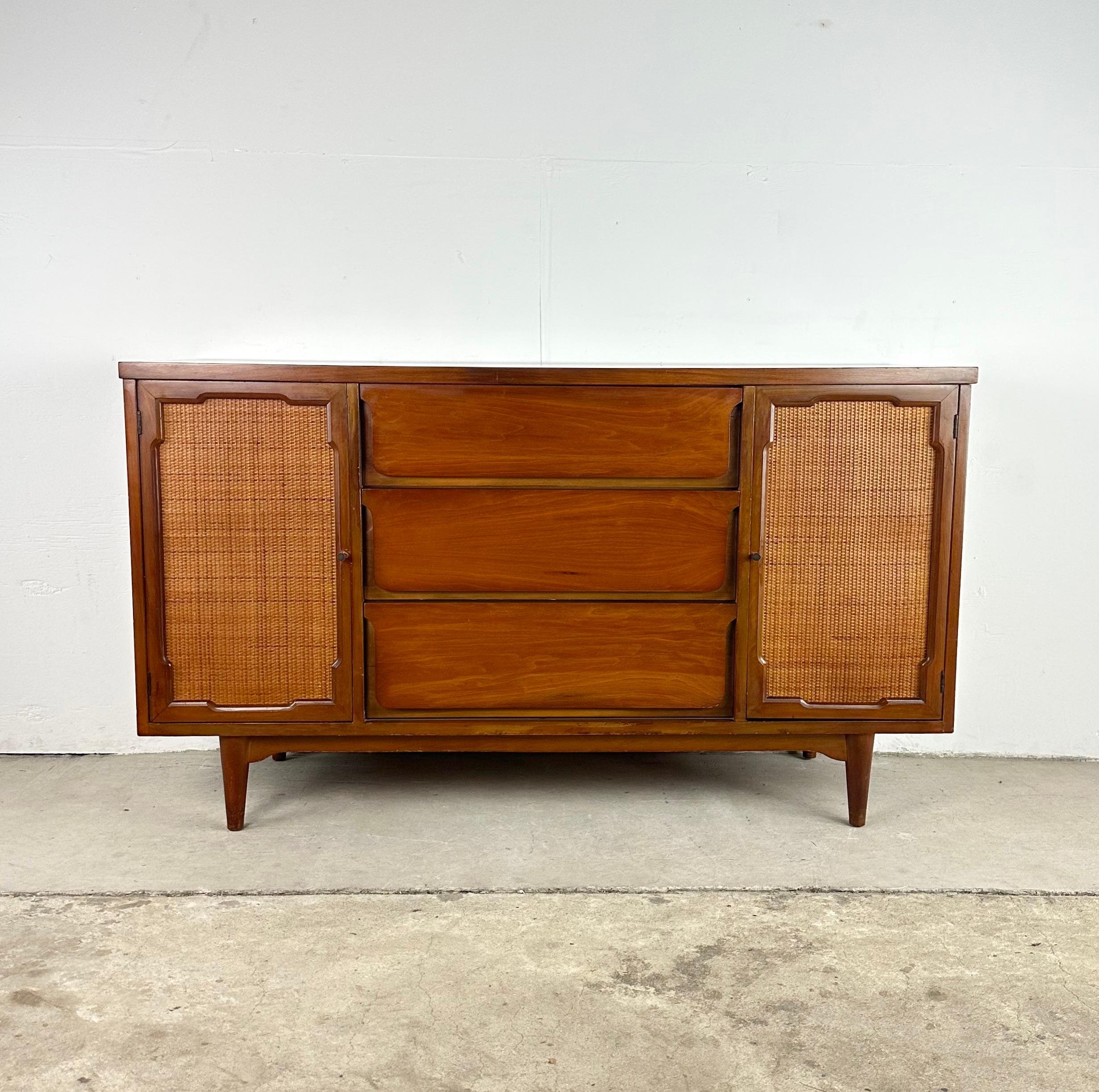 Uncover a blend of functionality and mid-century style with this simple yet striking vintage sideboard. This server boasts clean lines and organic tones- cane doors not only add warmth but also a touch of texture to your space.

The marriage of wood
