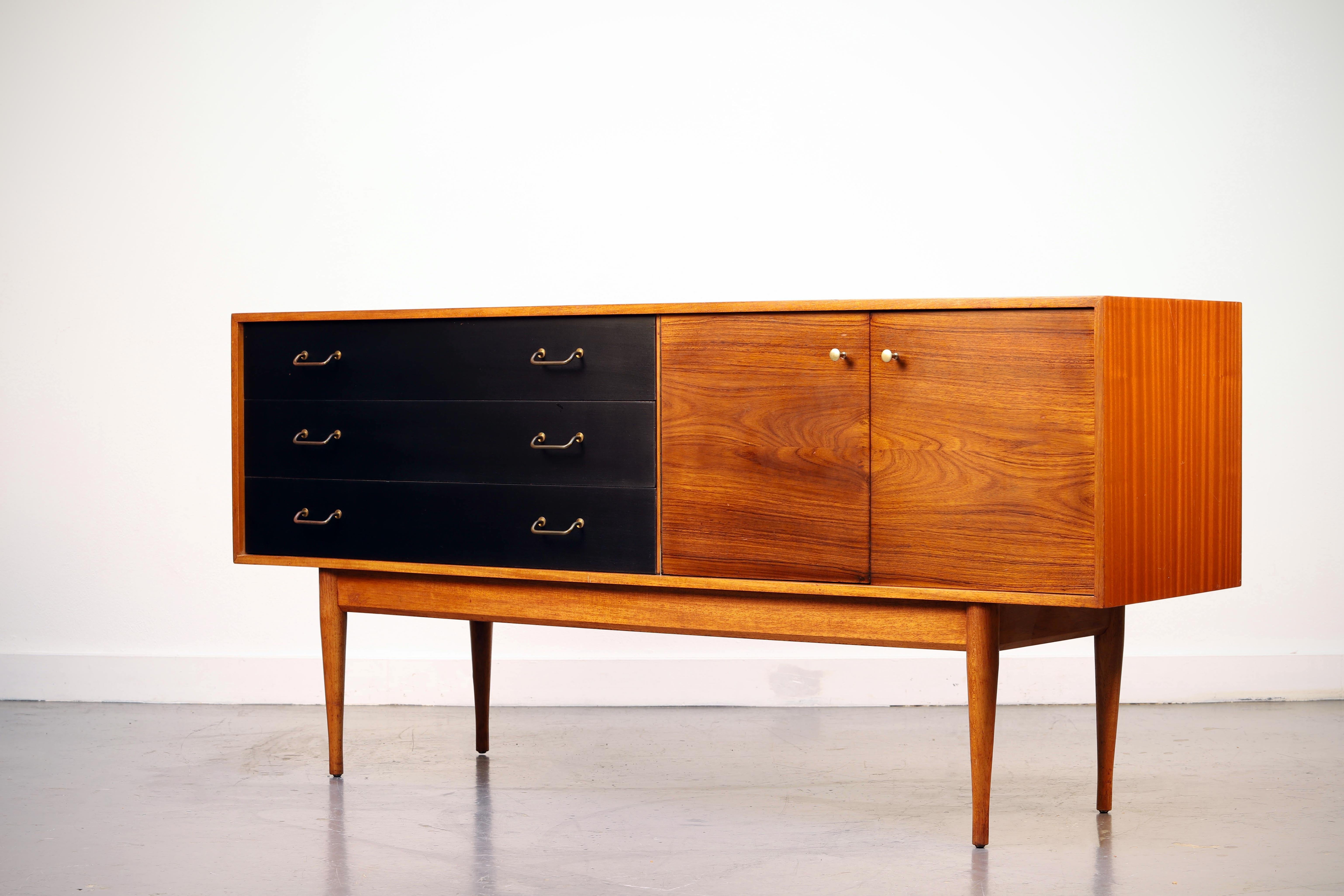 This is a superb vintage sideboard in rosewood and mahogany, it was made by Uniflex. Beautiful color, impressive grain patterns, and also has a black finish on the drawers.
 