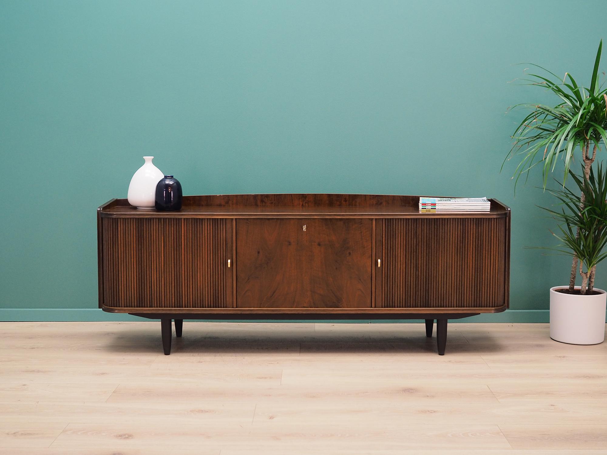 Outstanding sideboard from 1960s-1970s. Scandinavian design, Minimalist form. Surface of the furniture is covered with walnut veneer, legs are made of solid walnut wood. Sideboard has two drawers behind stylish doors, in the middle there is an