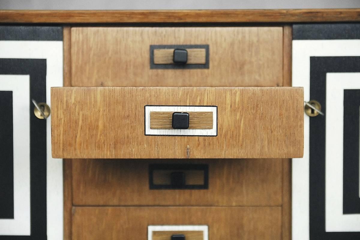 This Modern style sideboard was manufactured in Scandinavia in the 1960s. It is made from walnut and walnut veneer with strong grain. The unit has two lockable doors with keys and four drawers. The front is decorated with a hand-painted pattern, and