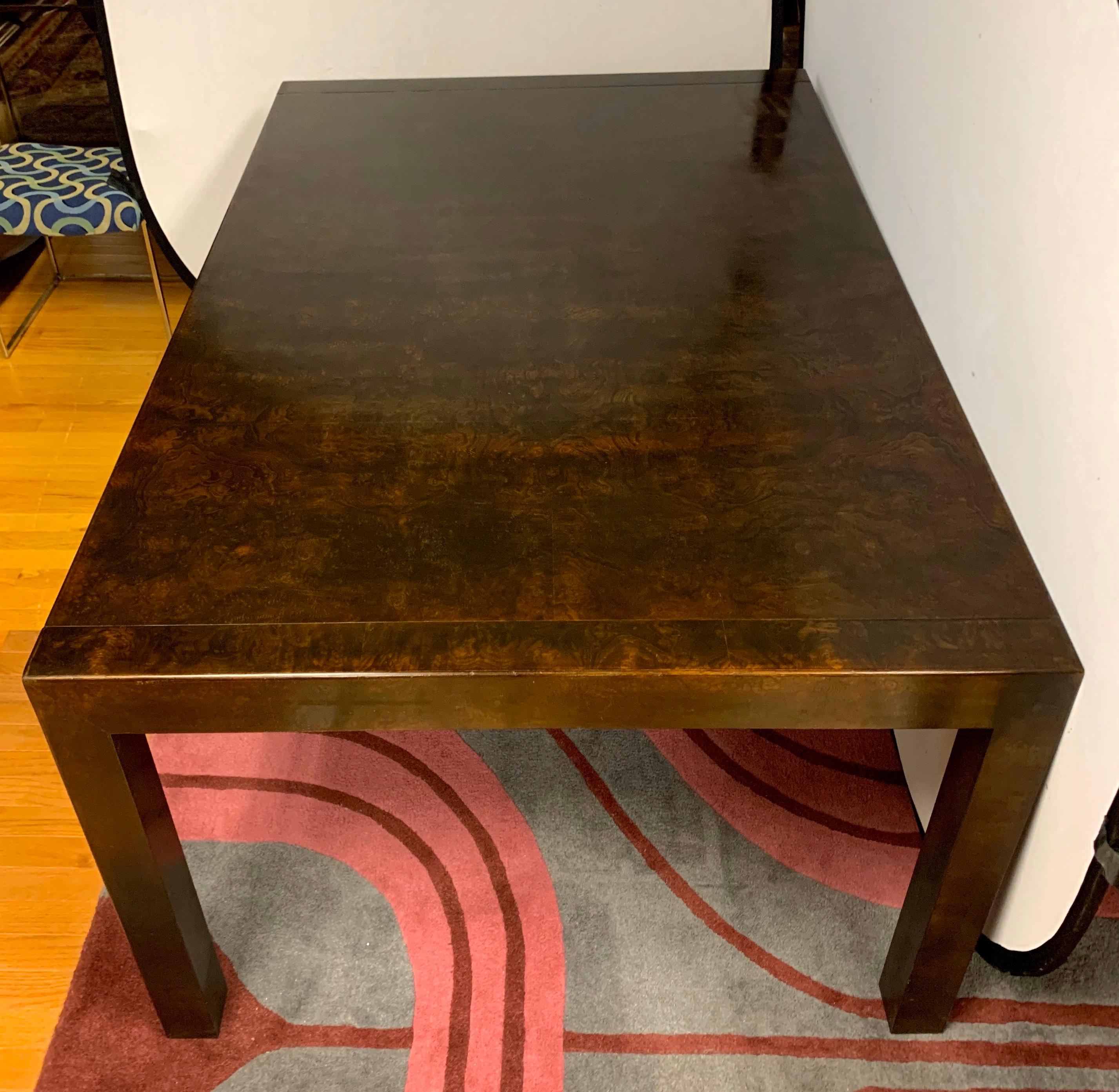 Elegant signed John Widdicomb expandable burl wood dining table. It comes with two, 20 inch leaves that take the table from 63.5 inches up to 103.5 inches when both leaves are in. The color is a dark brown and it has only age appropriate wear. In