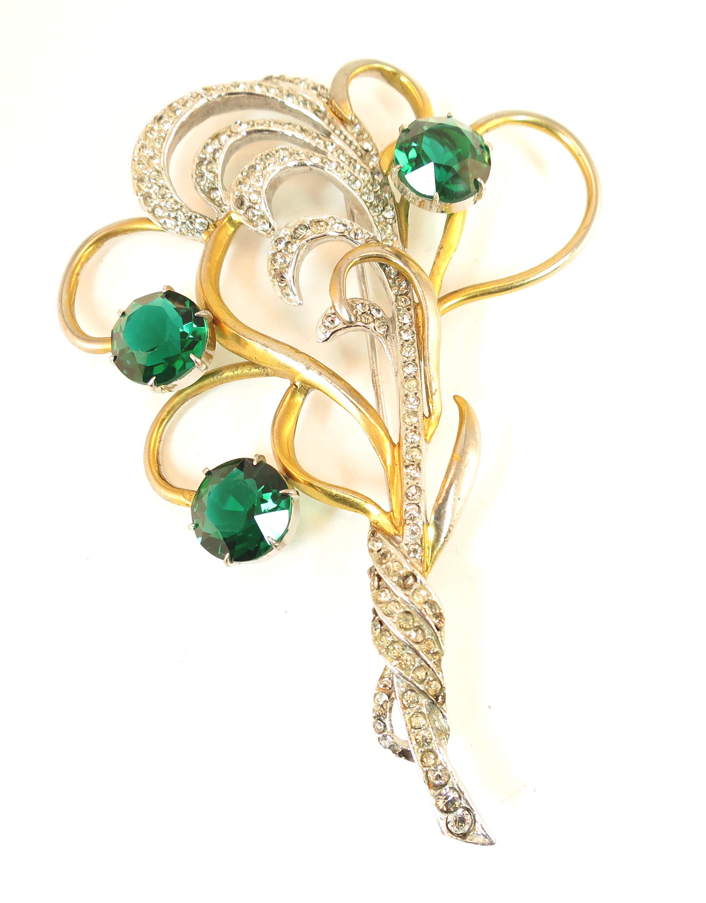 Offered here is a large Mid-Century Silson rhodium-plated sterling brooch with large emerald crystals from the 1940s. The stylized gathered bouquet design is expressed through gold-plated winding tendrils, with a silver spray of pave-set clear