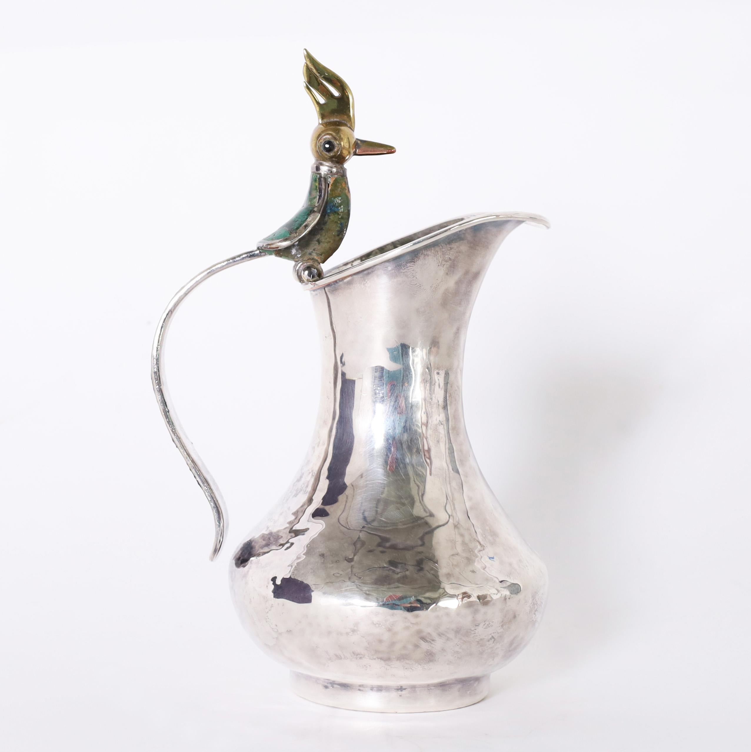 Two piece Vintage cream pitcher and sugar bowl having a pitcher hand crafted in silver over copper with a stone clad bird as a handle and a hand crafted sugar bowl with a stone handled lid, spoon and stone clad bird handle. Signed Los Castillo on