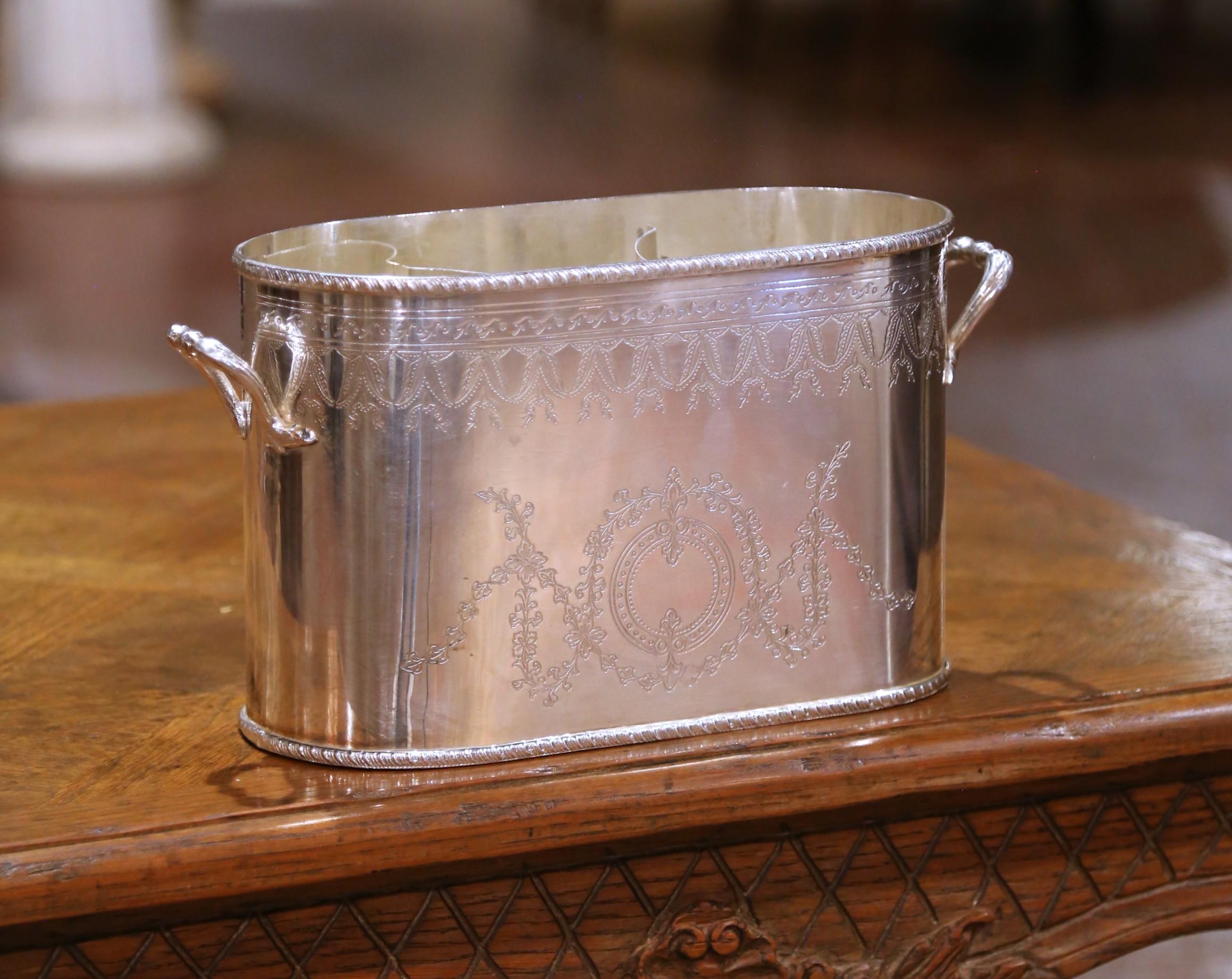 Realizzato in Inghilterra a metà del XX secolo, questo elegante portabottiglie in argento di International Silver Co. unisce una funzione raffinata a uno stile senza tempo. Il corpo ovale allungato è ornato da intricate incisioni in stile