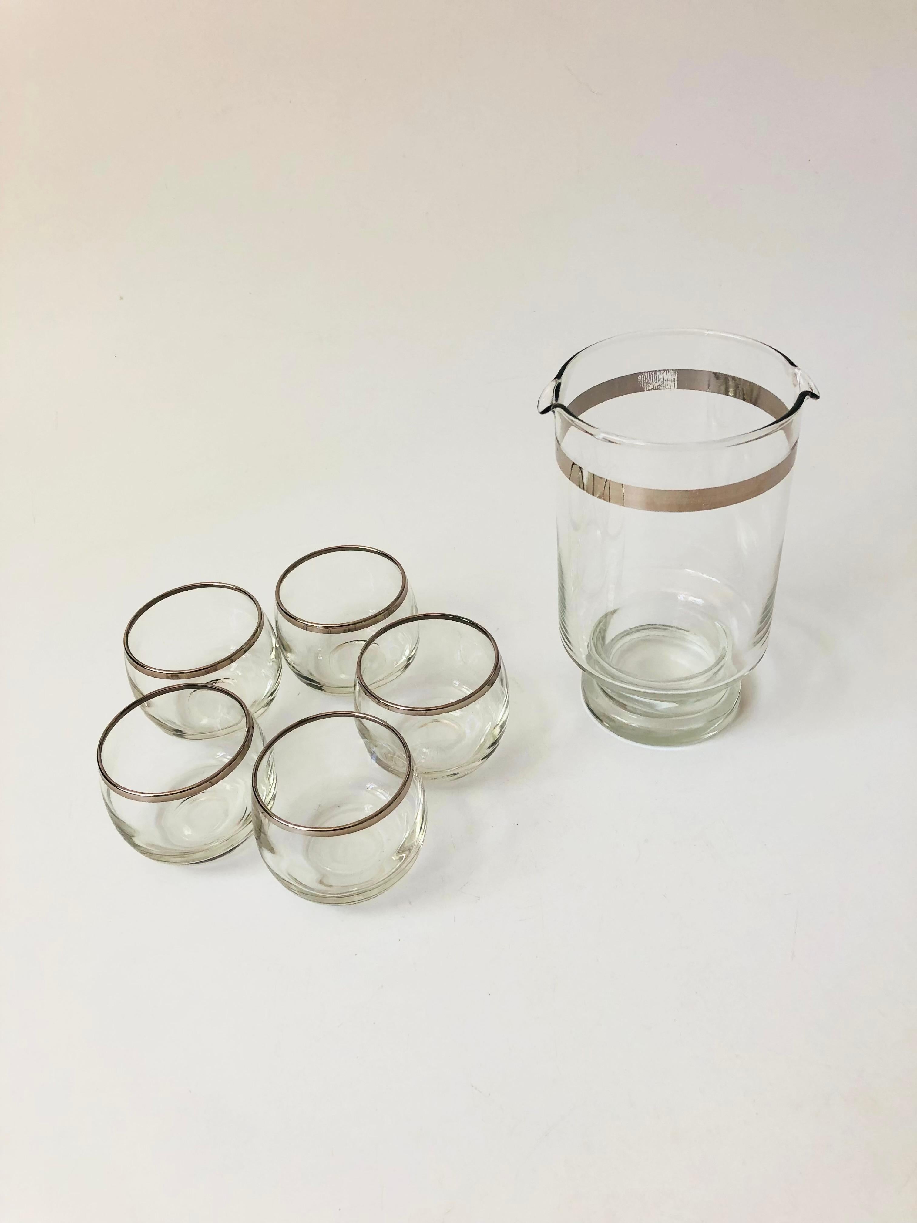 A mid century silver rimmed cocktail set. Includes a double spouted pitcher and 5 roly poly cordials. Metallic silver trim decorates each piece.
Measurements:
Pitcher: 4.25