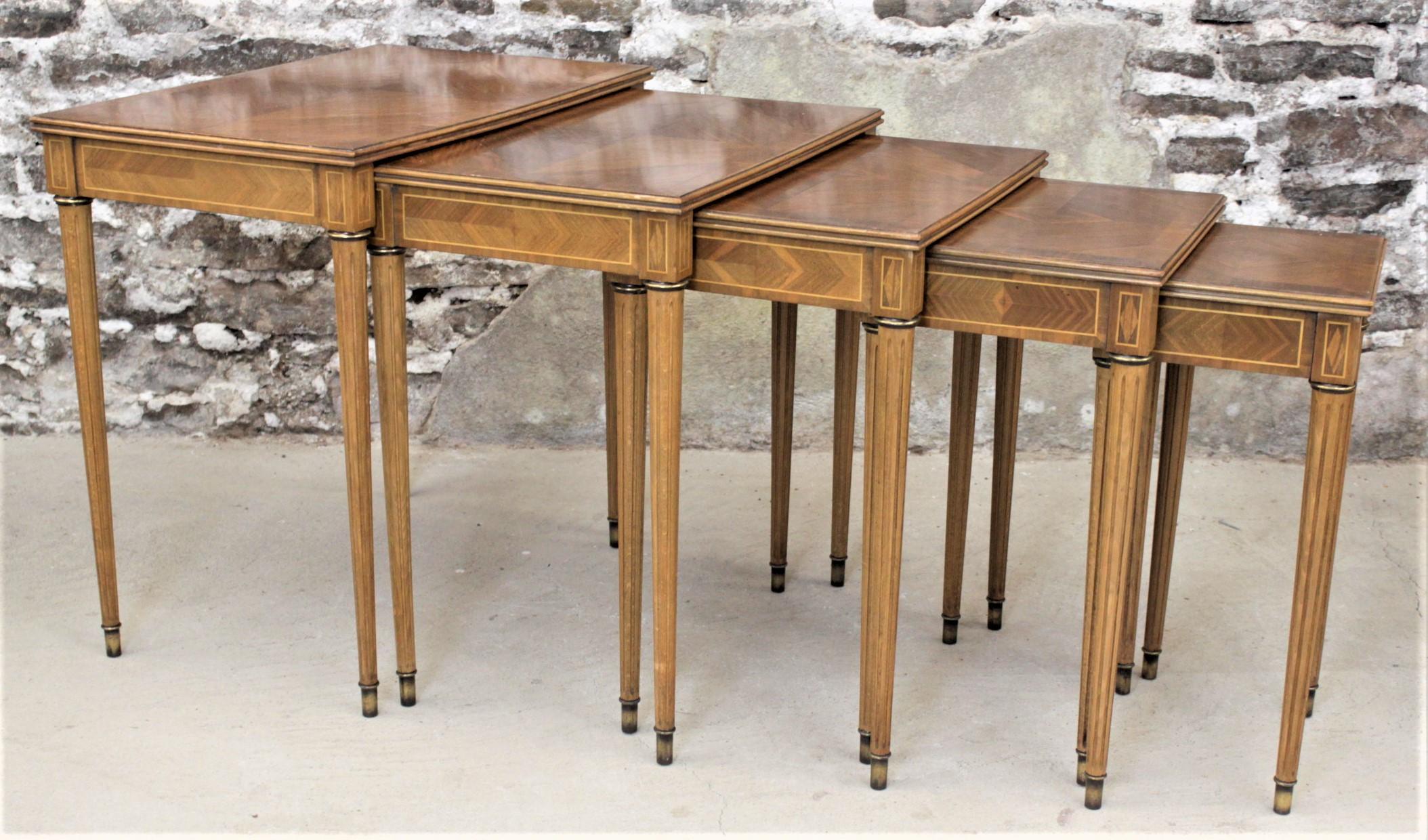 This set of five mid century era nesting tables were made by the Simon Loscertales Bona design firm of Spain in approximately 1965 in a Neoclassical Revival style. The tables are constructed of wood with marquetry veneer on the tops and skirts and
