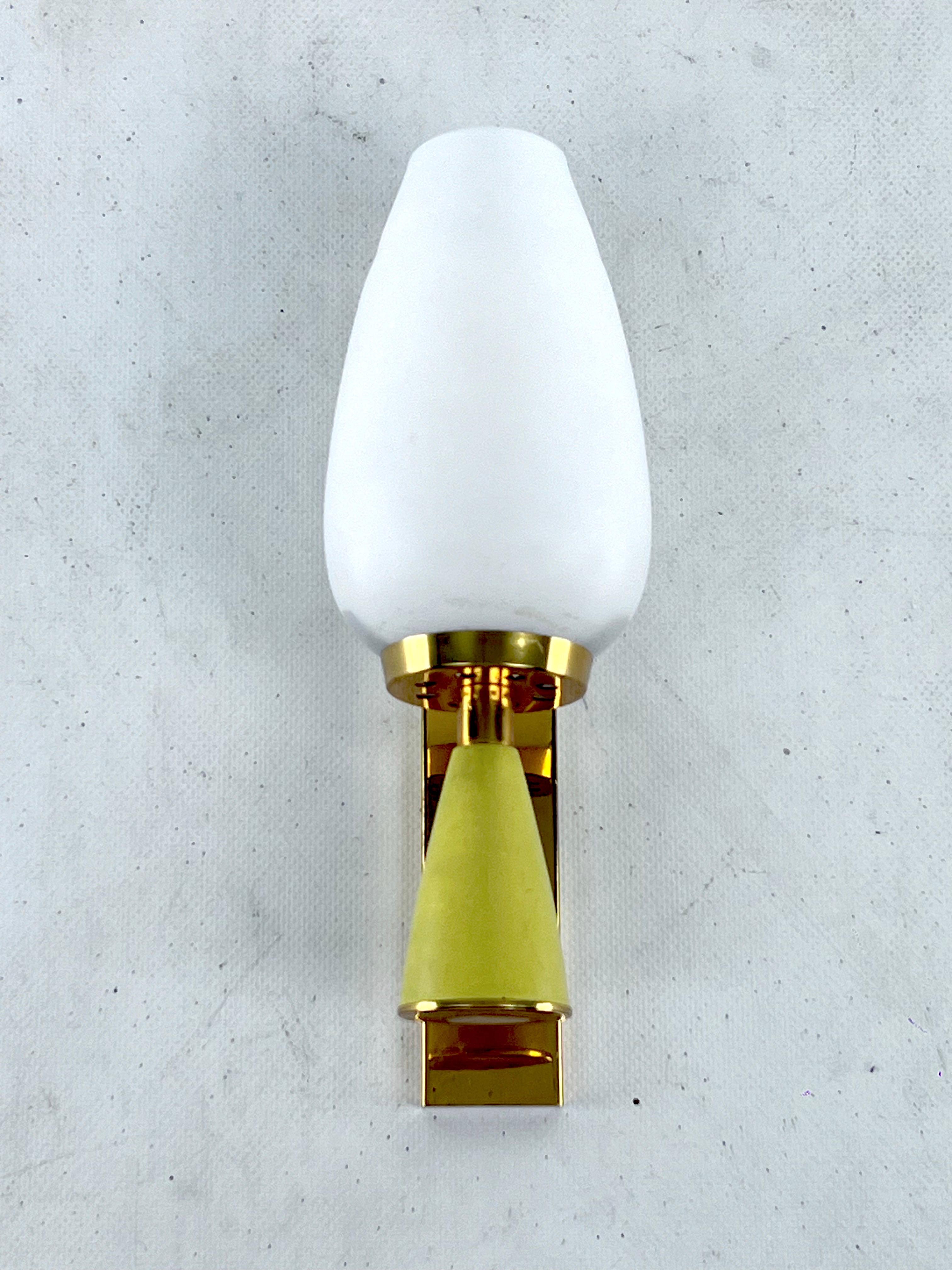 Reminiscent of Stilnovo manner, this sconce was produced in italy during the 50s. Made from brass, lacquer and opaline glass. Trace of age and use. Full working with EU standard, adaptable on demand for USA standard.