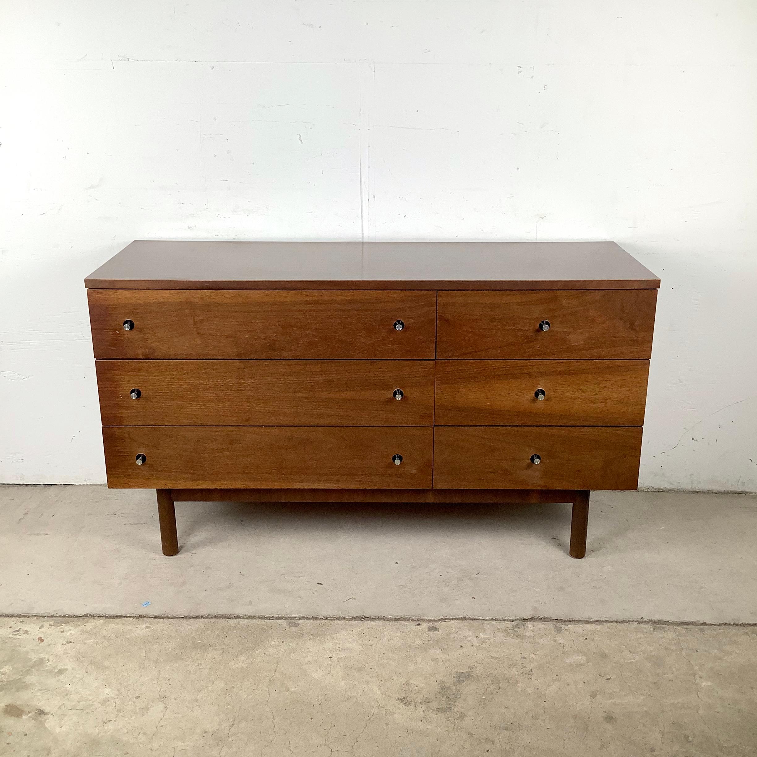 Esta cómoda baja de seis cajones de Stanley Furniture es un bello ejemplo del diseño americano de mediados de siglo. Definida por su carcasa de chapa de nogal y su práctica encimera de laminado de imitación madera, la pieza encarna tanto la estética