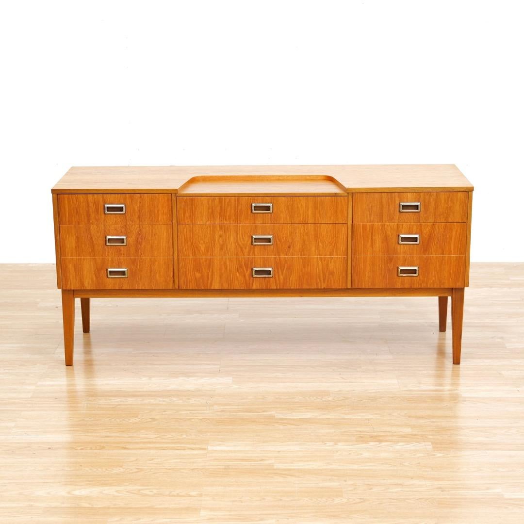 Questo comò d'epoca a sei cassetti è stato progettato e prodotto in Inghilterra negli anni '60.  Realizzato in teak, questo comò si presta a diversi utilizzi: è ideale come console d'ingresso, comò per la camera da letto o per il soggiorno.