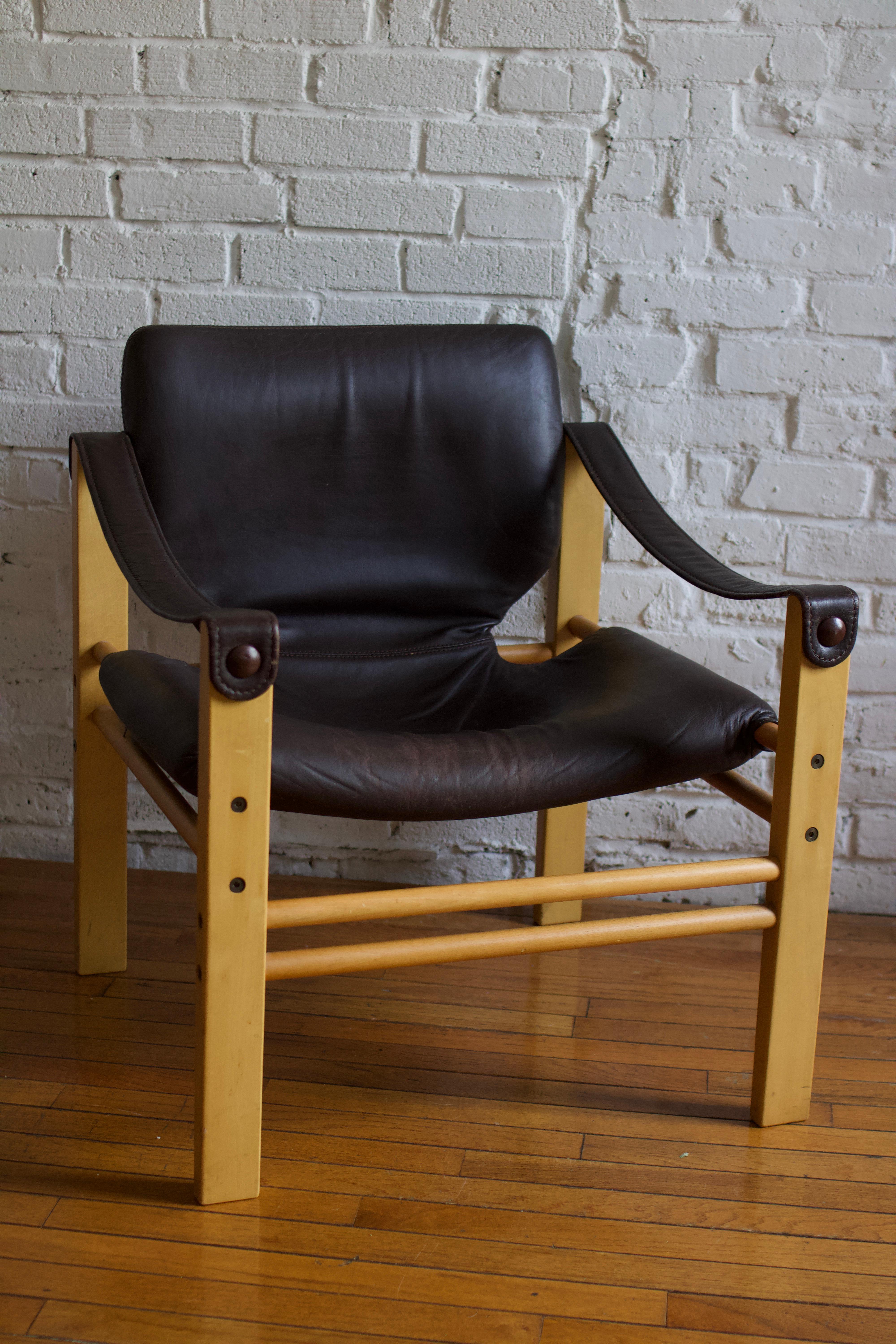 Special mid-century modern safari lounge chair made in Europe, circa the 1960s. The piece features its original cognac faux leather, a sturdy wood frame, stylish curves, and steel screw details. The chair is also impressively comfortable. 

Ships
