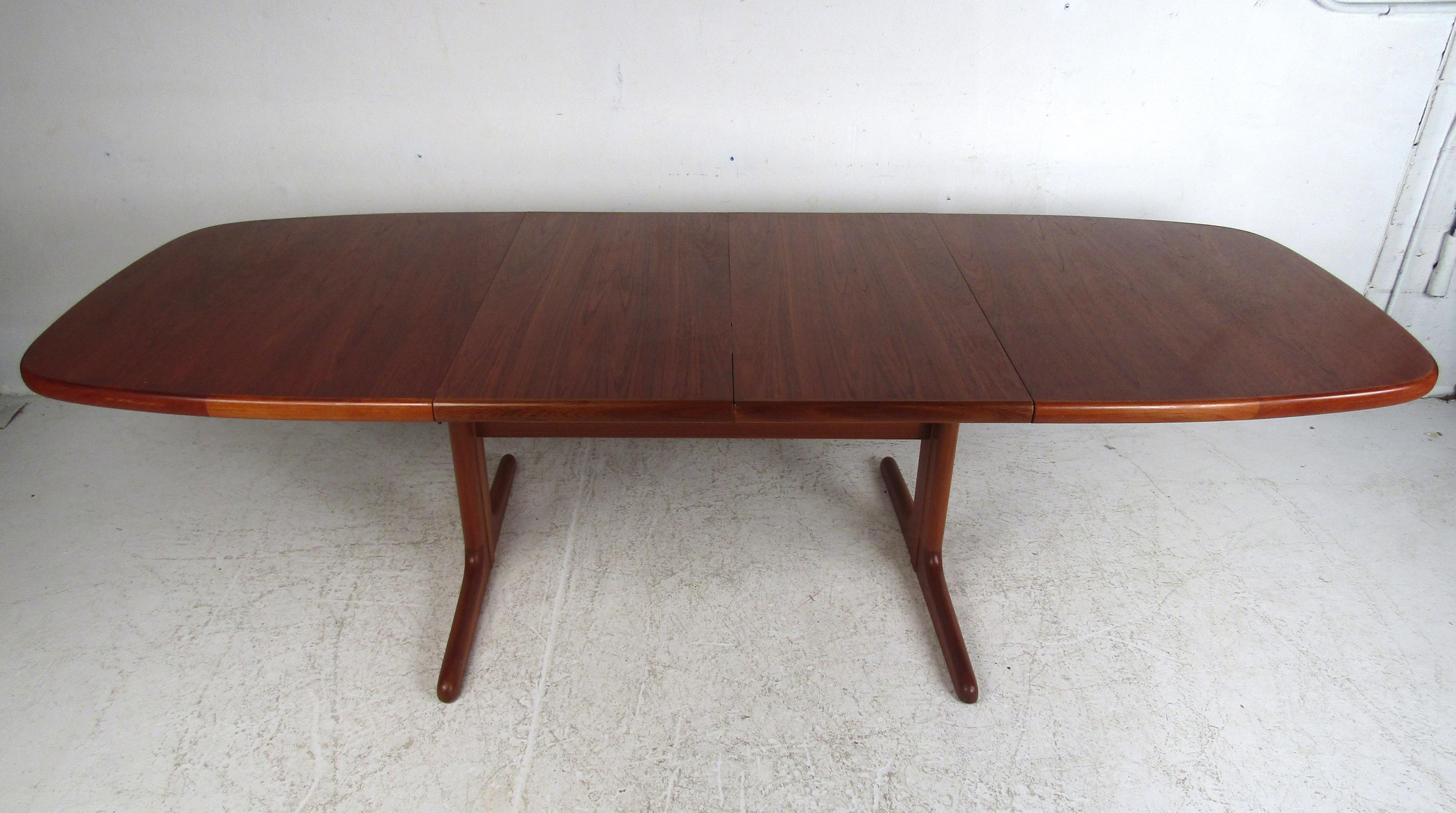 This stunning vintage Danish modern dining table boasts an unusual sled leg base with a stretcher that runs horizontally for added support. Two leaves enable this dining table to extend from 65 inches wide all the way to 104.5 inches wide ensuring