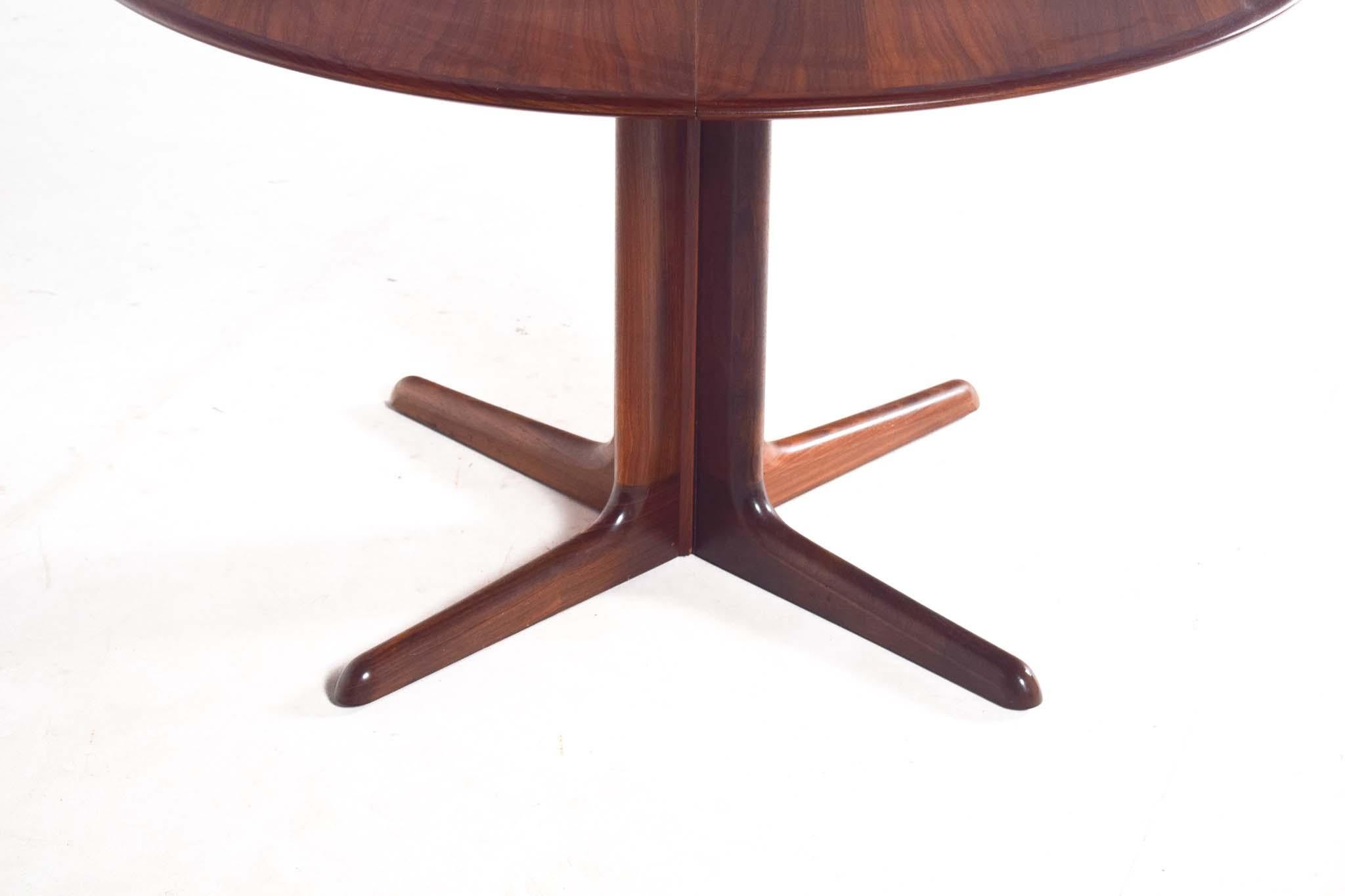 Mid-Century Modern dining table by Skovby features a round rosewood top with two extendable leaves, allowing it to transition seamlessly from an intimate setting to accommodate larger gatherings. The rich rosewood grain exudes warmth and elegance,
