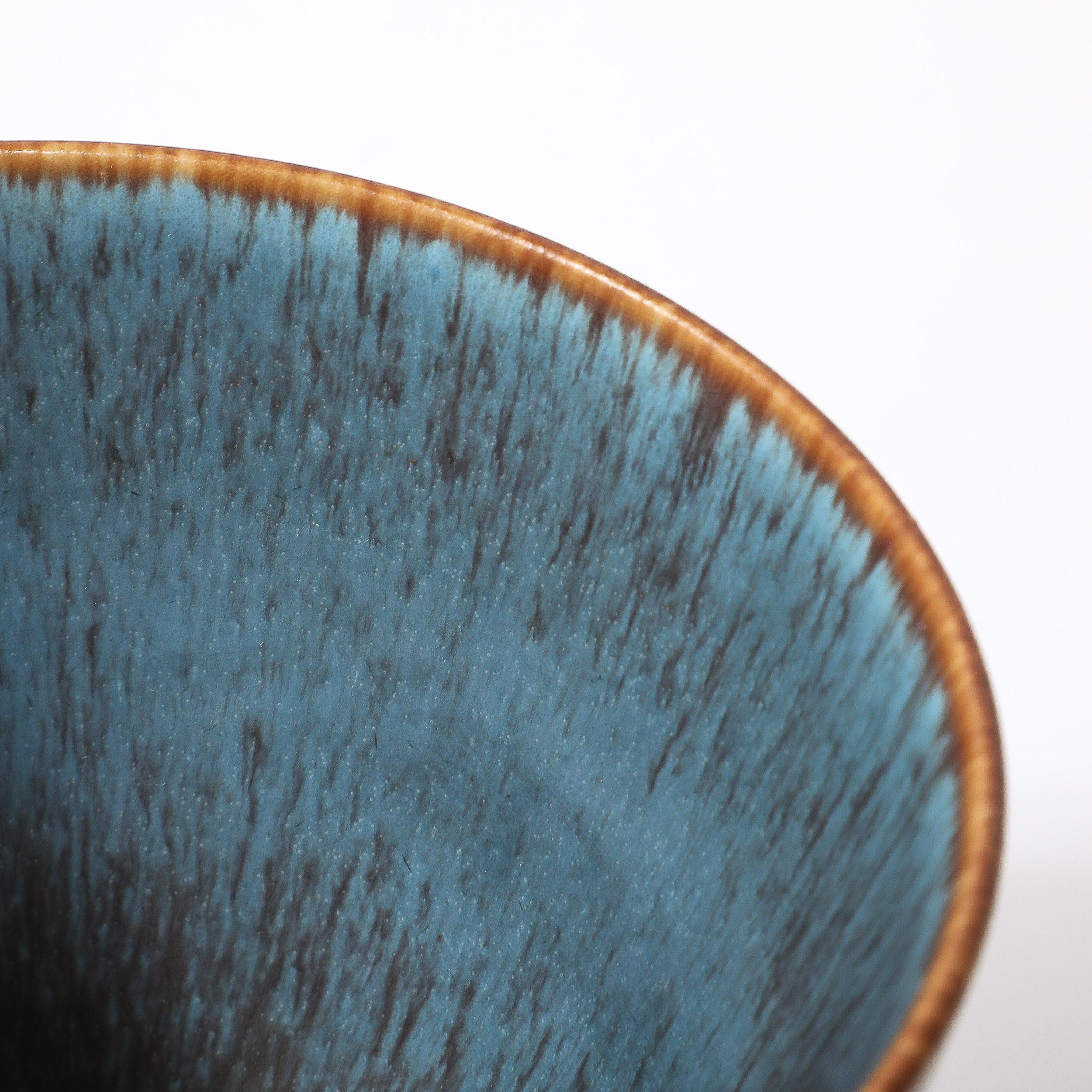 This lovely Mid-Century Modernist Sky Blue and Copper Glazed Ceramic Bowl by Gunnar Nylund for Rörstrand originates from Sweden, Circa 1950. This bowl features beautiful proportions and stunning striated textural detailing along the rim, revealing a