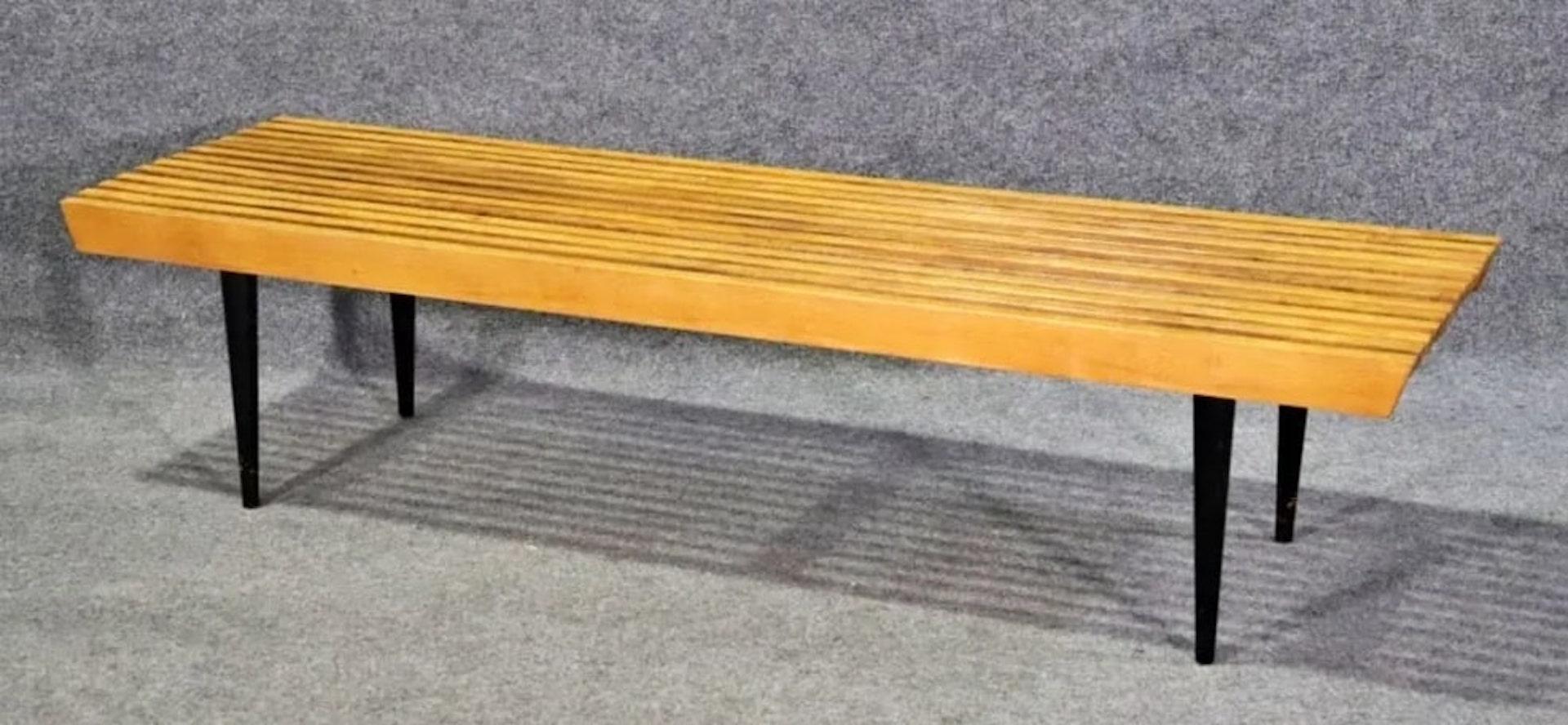 Mid-century modern slat bench in the style of Herman Miller. Blonde top on black tapered legs.
Please confirm location NY or NJ