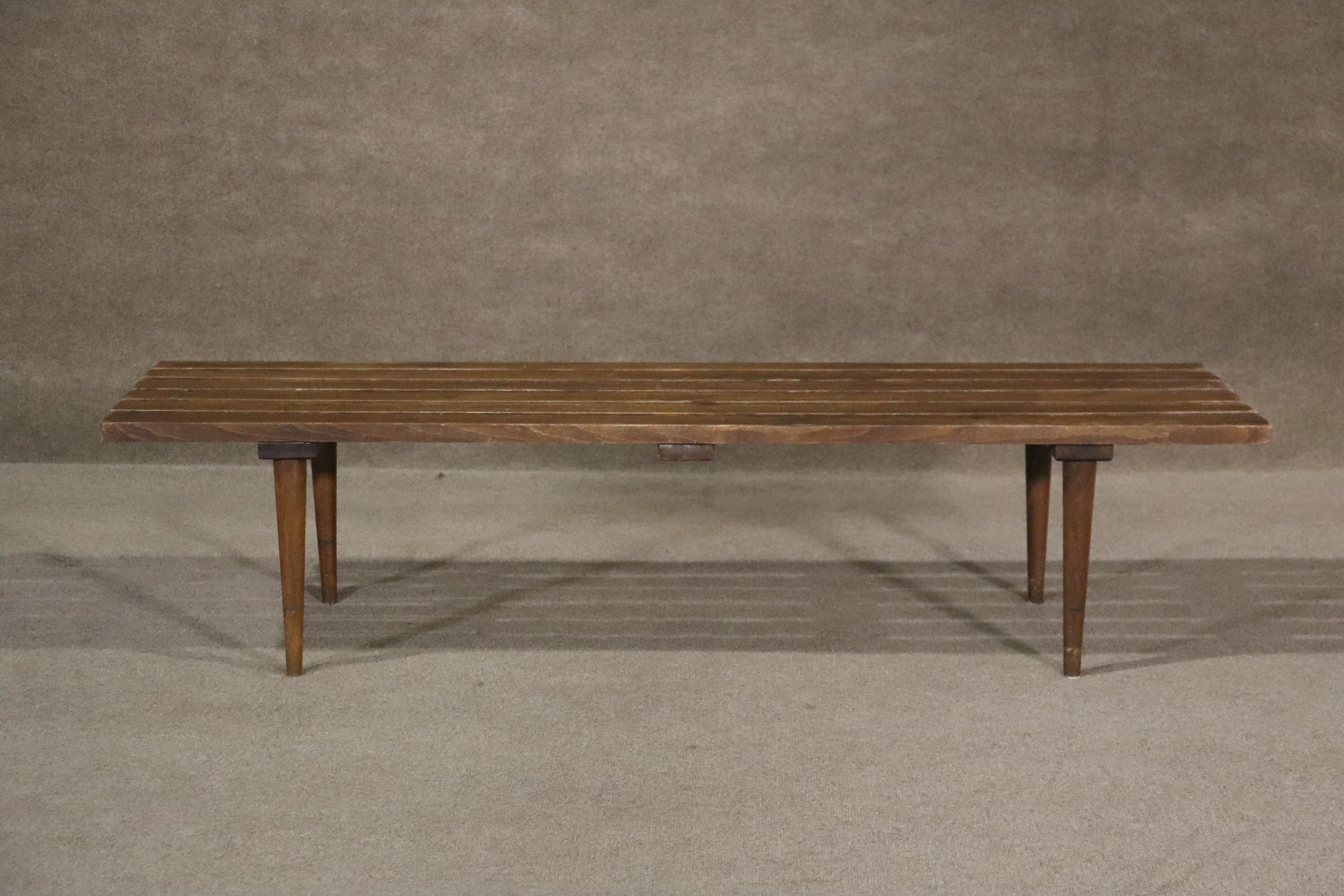 Sturdy walnut slatted bench at an ideal height for both seating and table use. Gorgeous mid-century details are great for living room use or entry way seating.

Please confirm location (NY or NJ)