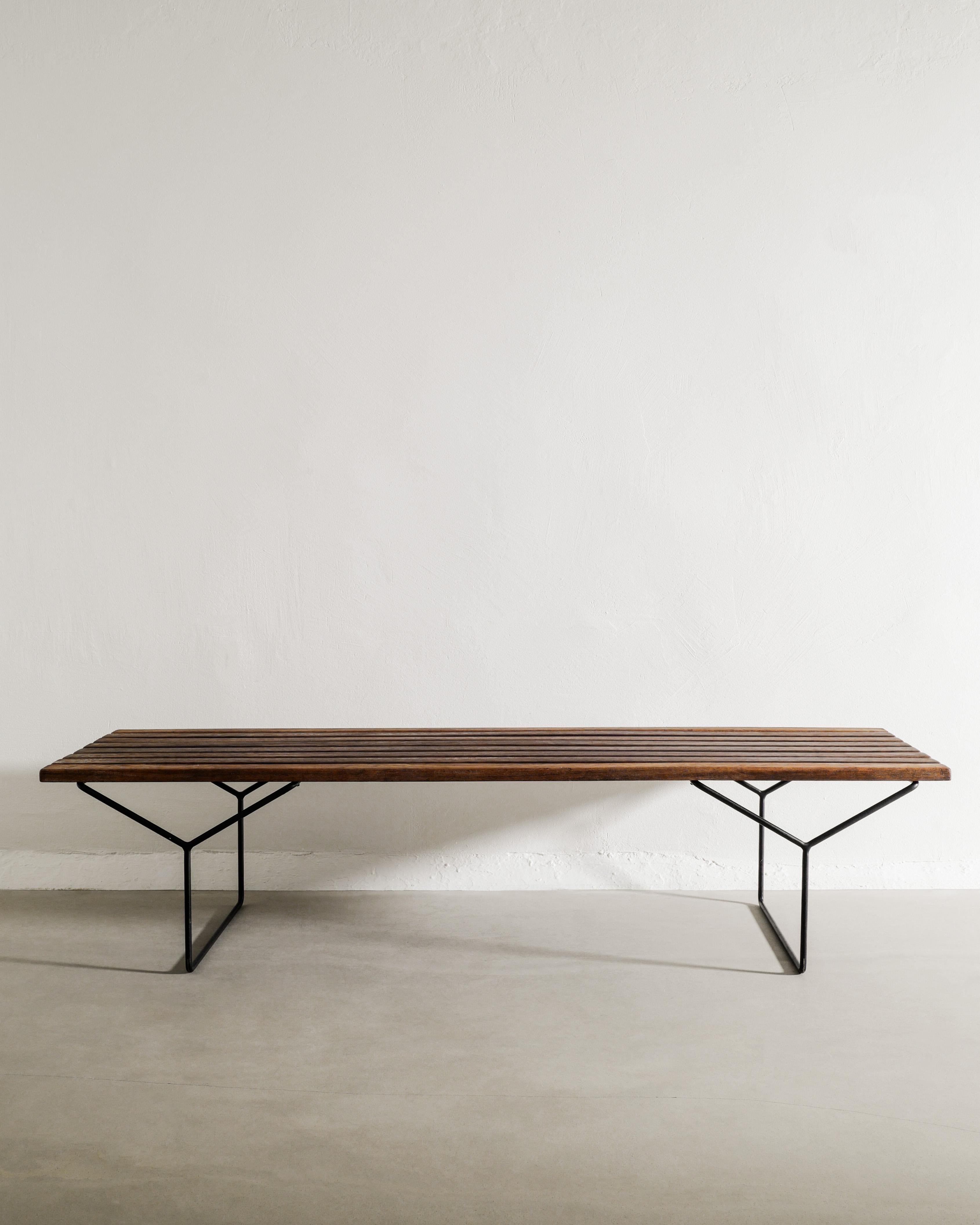 Rara panca a doghe in legno della metà del secolo scorso in teak marrone scuro e base in metallo laccato nero di Harry Bertoia prodotta e marchiata da Knoll International, anni Cinquanta. In ottime condizioni vintage con una leggera e bella patina