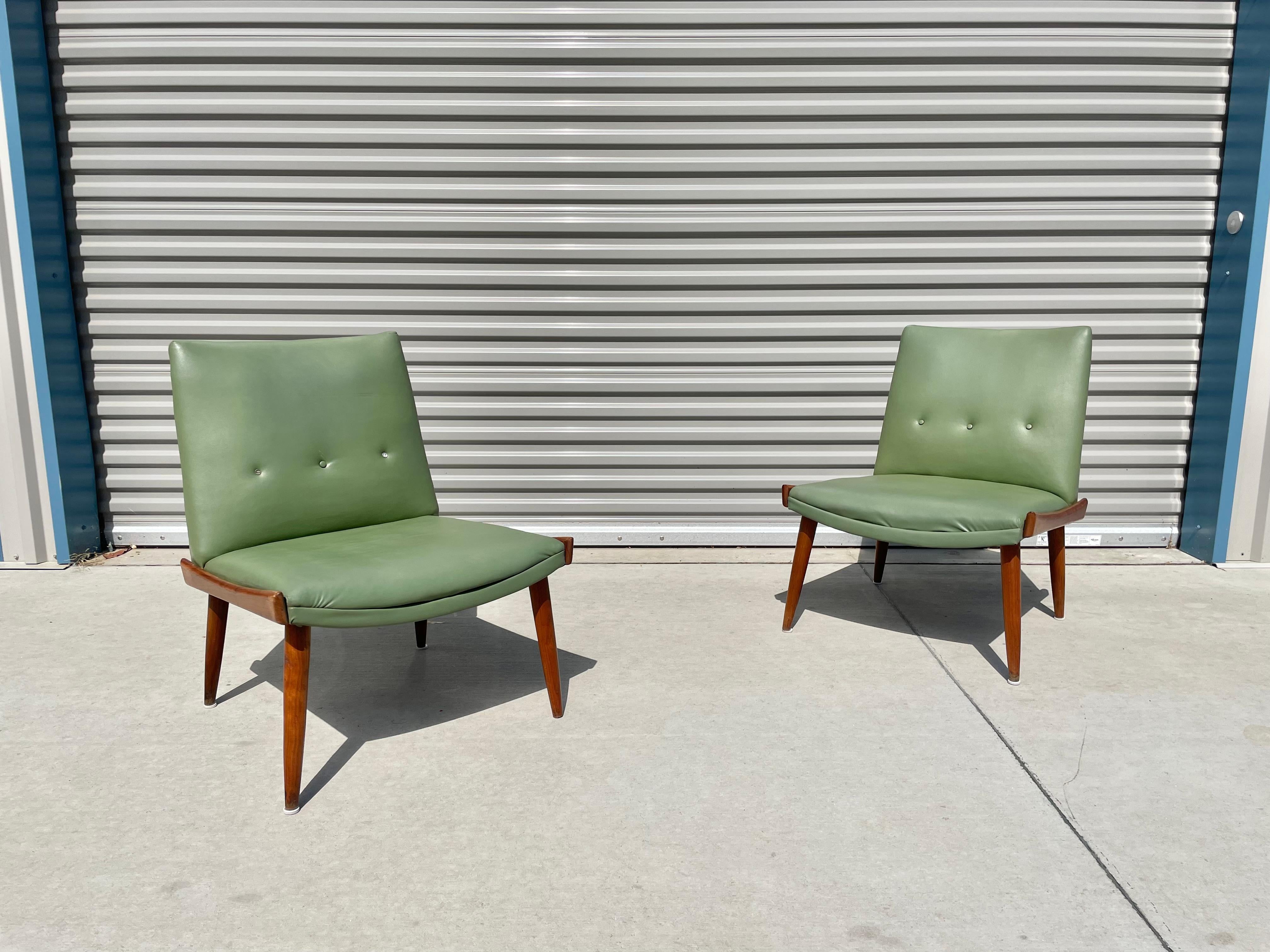 Stunning midcentury slipper chairs designed and manufactured by Kroehler Mfg Co. in the United States, circa 1960s. These chairs feature a beautiful green vinyl upholstery. The chairs also have two walnut slates on each side, giving them an