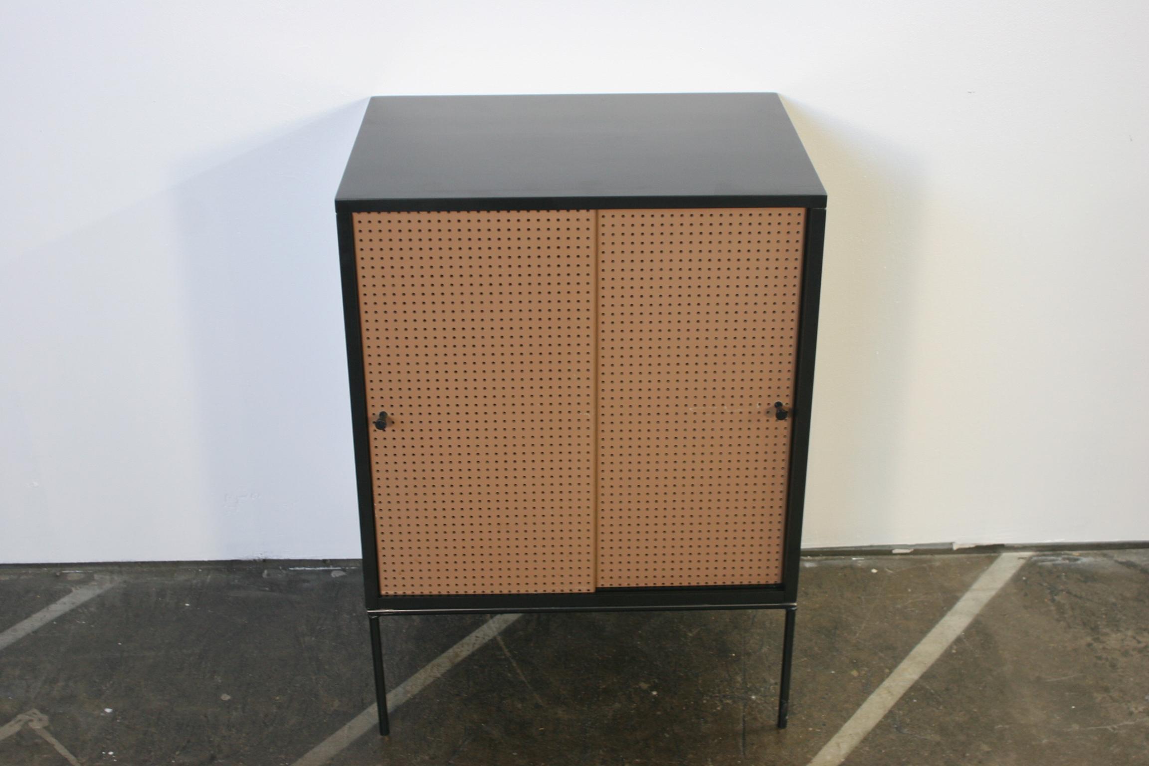 Beautiful midcentury small cabinet by Paul McCobb circa 1950 planner group #1512 has 1 shelve - solid maple construction has a black lacquer finish. Has very rare all original tan fiberglass perforated sliding front doors with black pulls sits on an