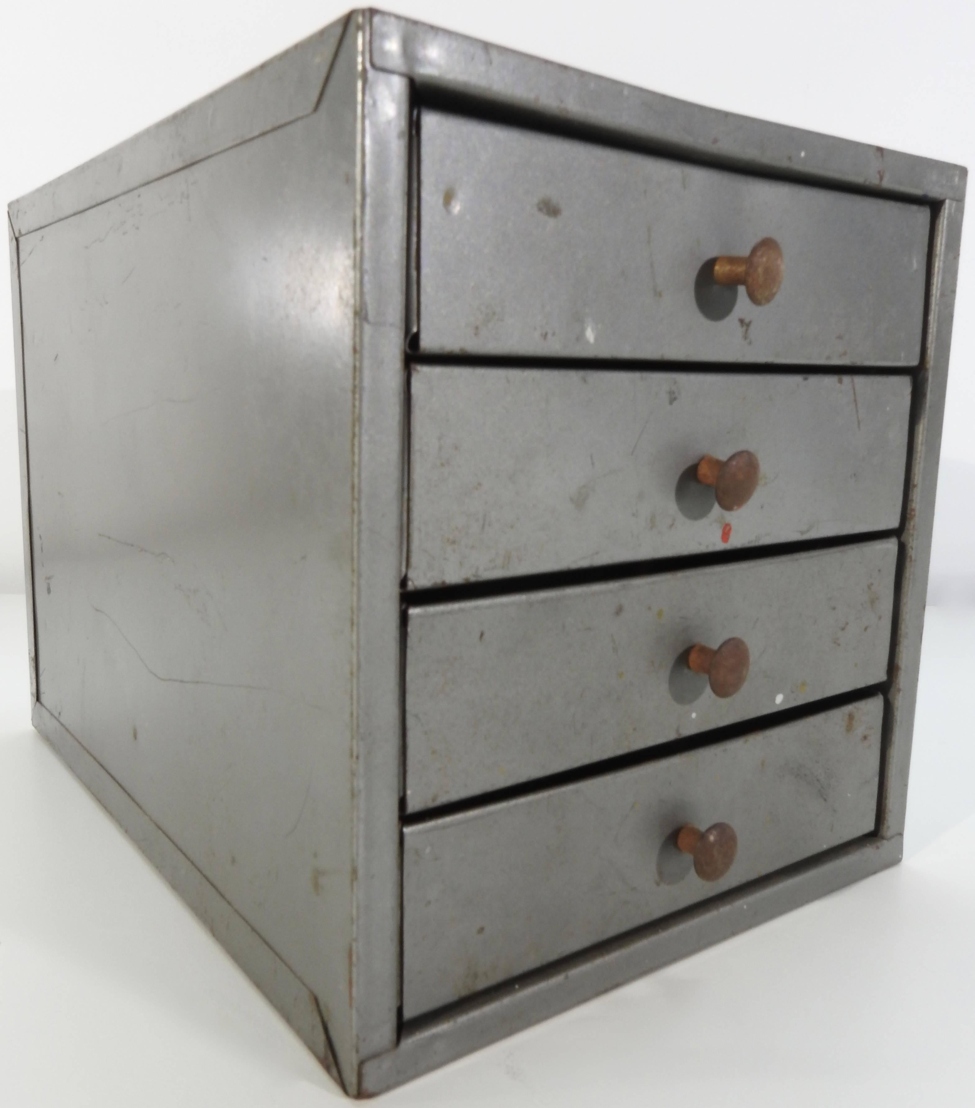 We are offering a small industrial metal box from the midcentury era. It feature four drawers with some partitions. Knobs serve to pull the drawers open. This would make for a unique desk accessory.