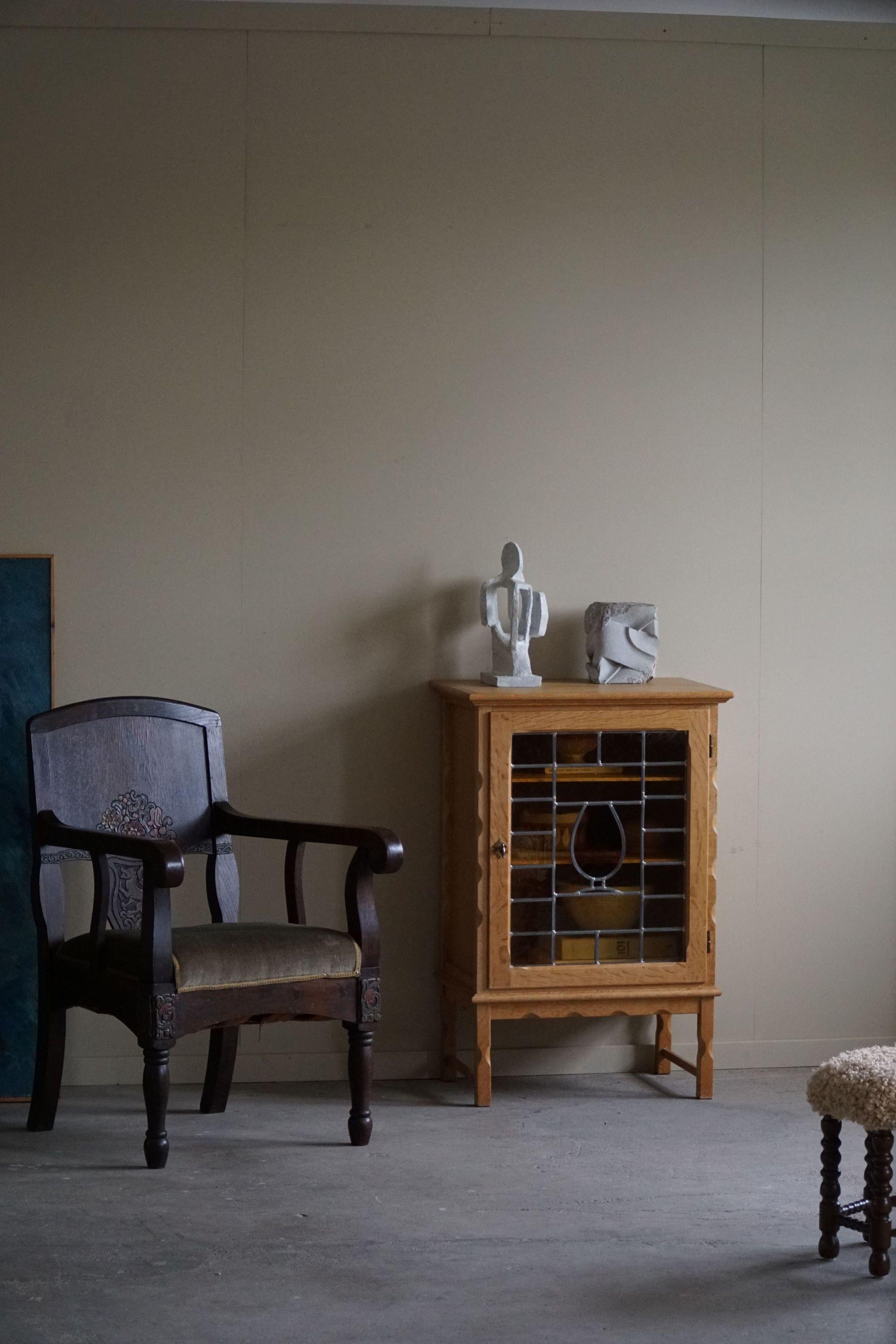 Se trata de un pequeño armario de roble de mediados de siglo, de la década de 1960, realizado por un ebanista danés. El mueble tiene un frontal de cristal coloreado, que permite ver los estantes interiores. Su diseño es minimalista, pero elegante y