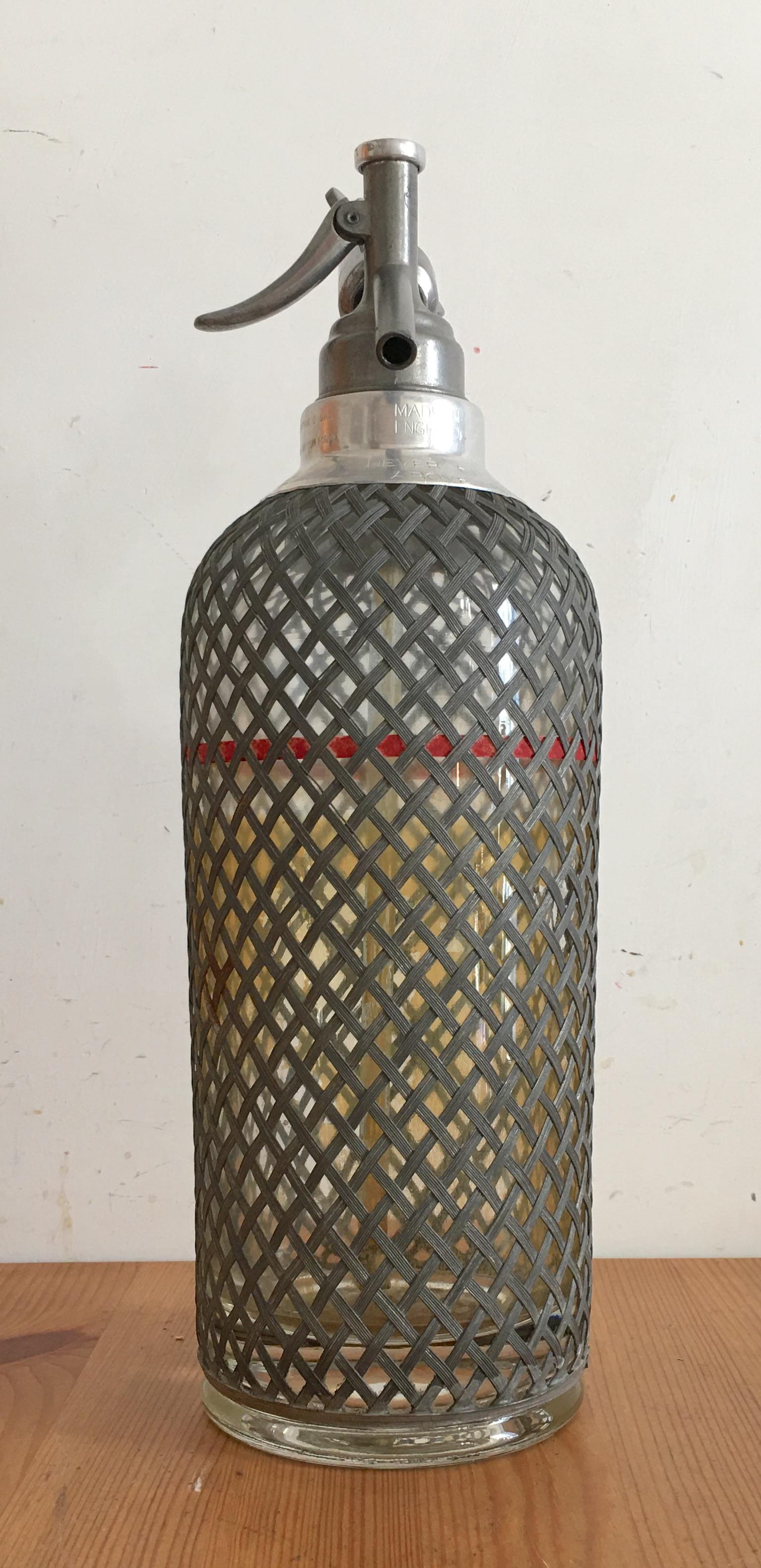 Bottiglia Seltzer in vetro ricoperto da rete di alluminio prodotta nel 20° secolo in buone condizioni, non collaudata nel funzionamento, oggetto da esposizione.